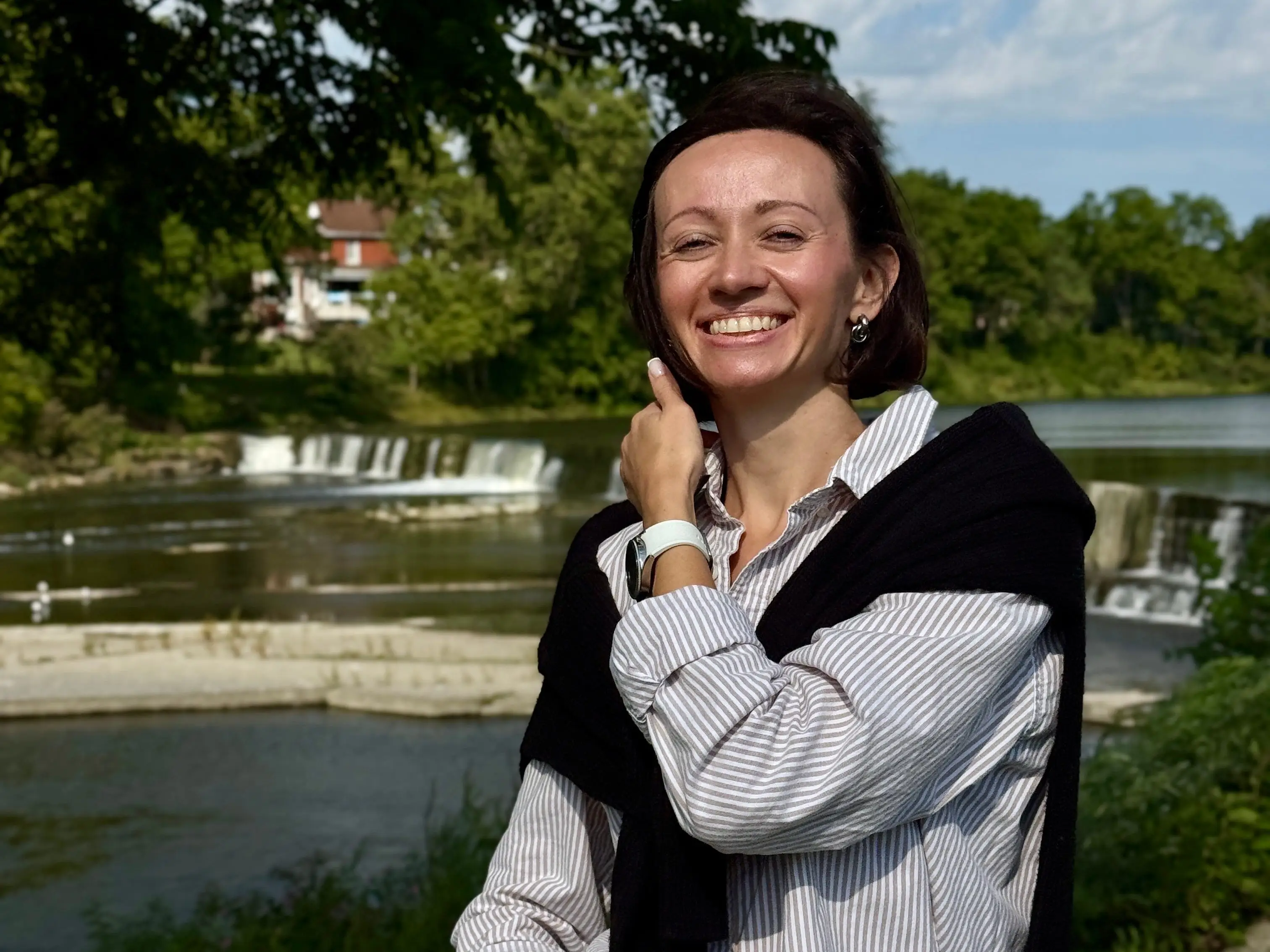 Alona Vasylieva in striped shirt and black sweater draped over shoulders.
