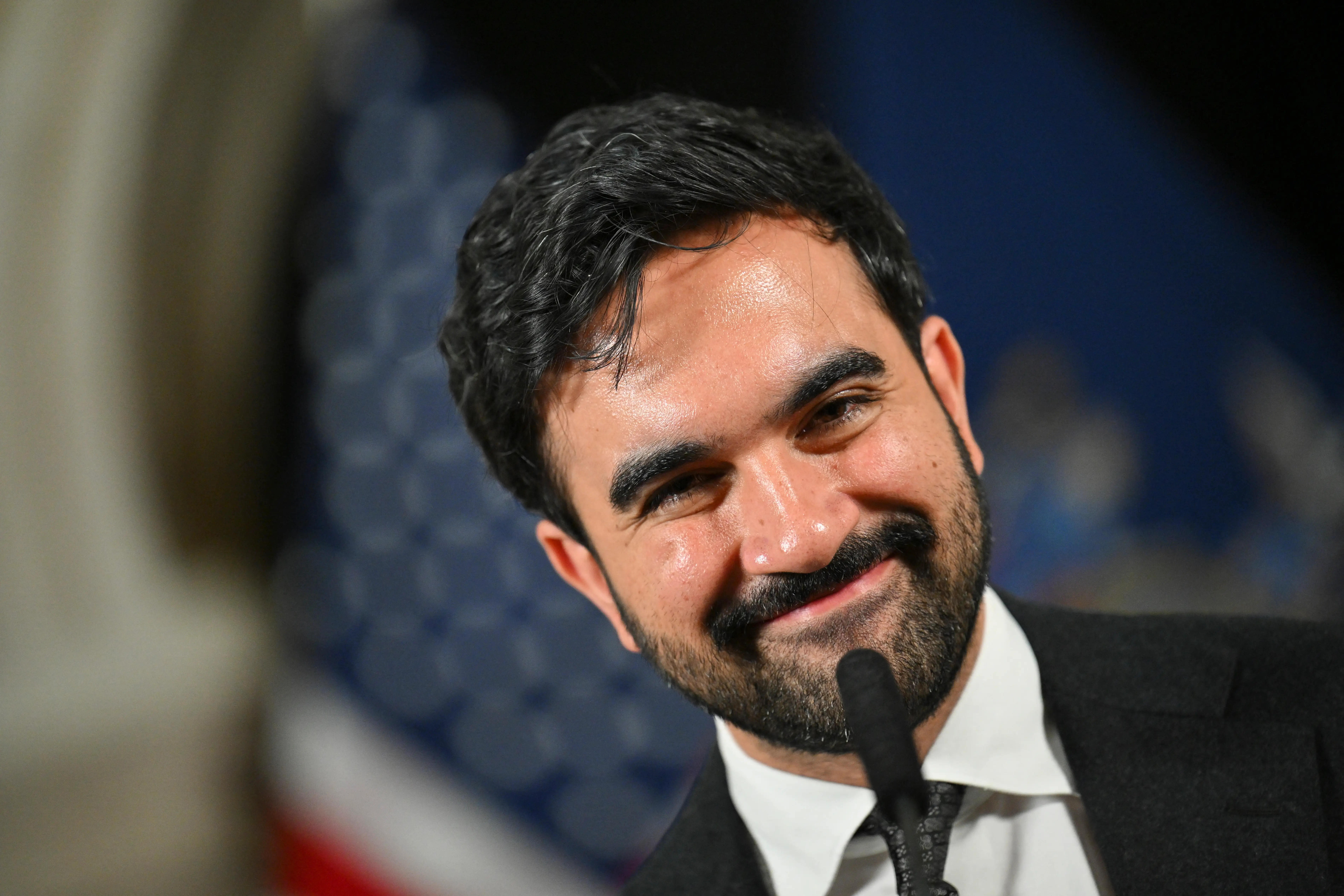 NYC Mayor Zohran Mamdani smiling into a microphone