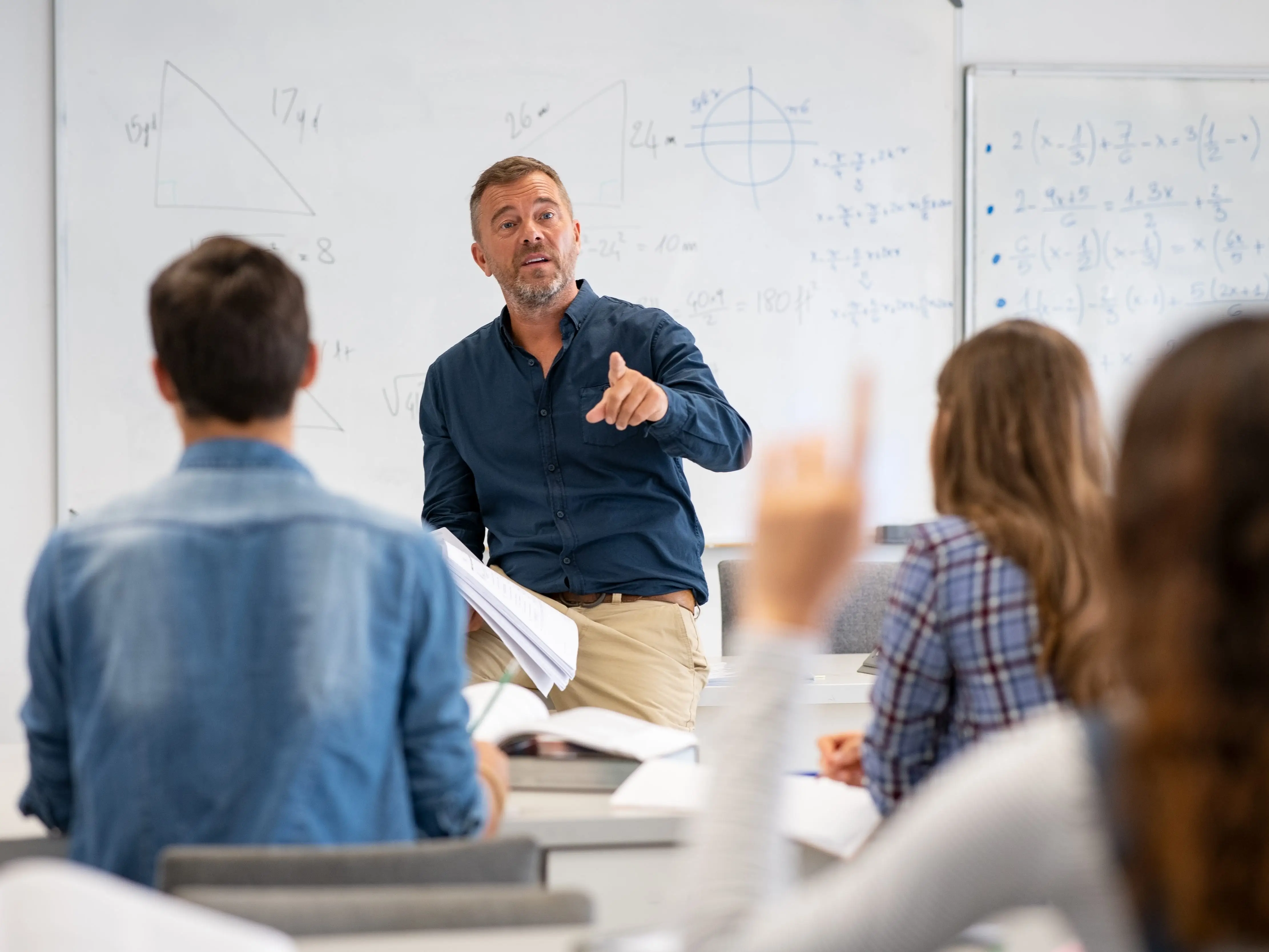 Student raising hand in classroom at the high school stock photo