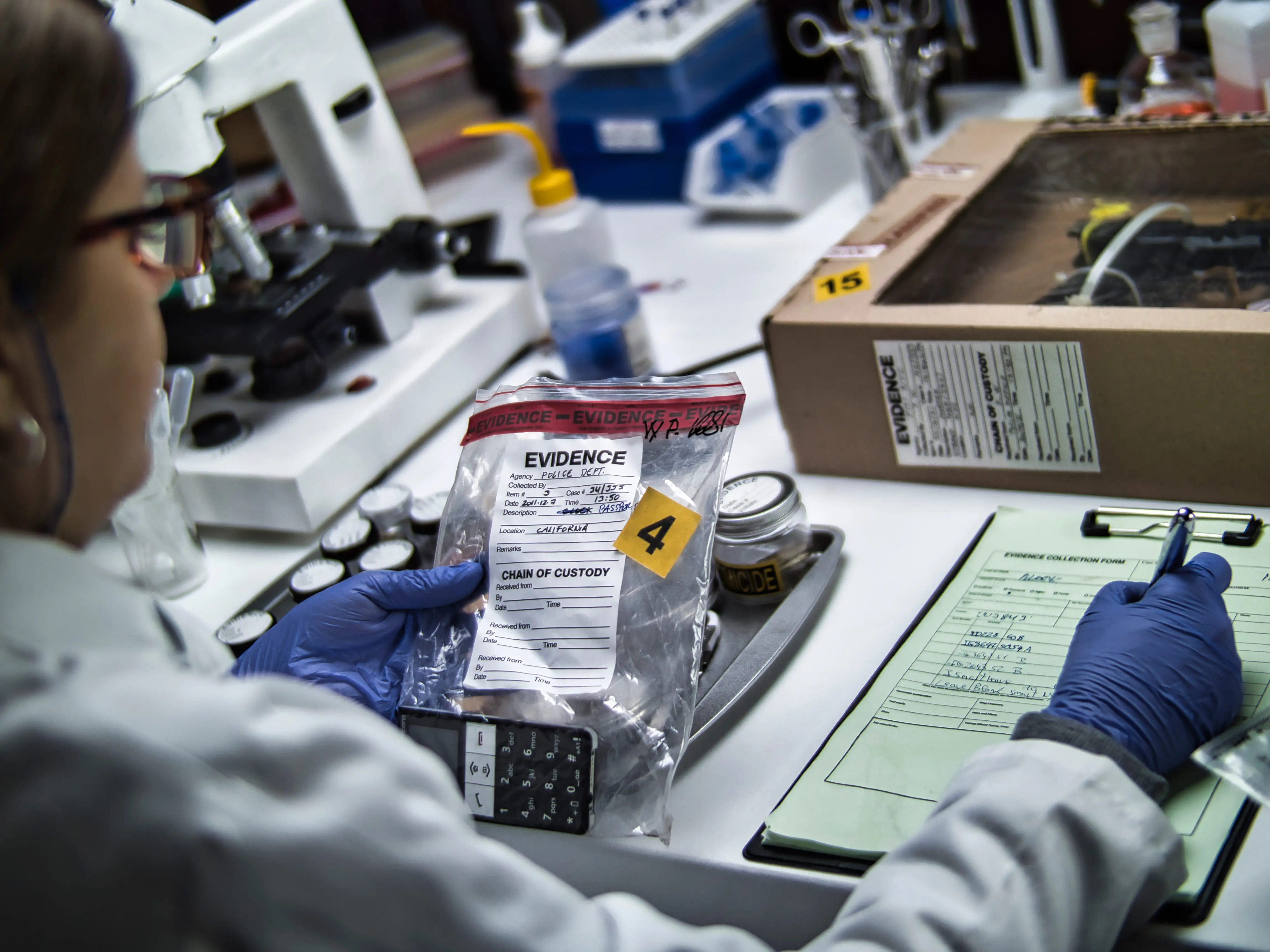 A police forensic expert is examining a mobile phone that is being used as evidence in a murder case stock photo