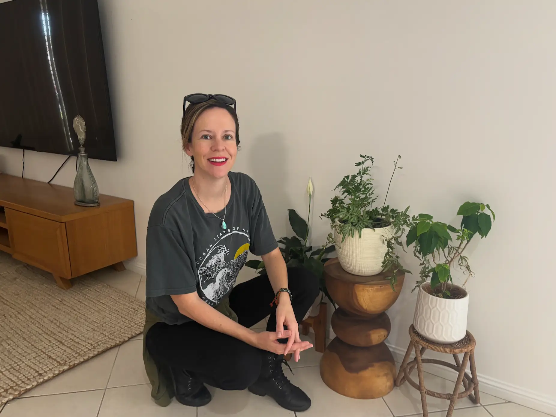 the author kneeling down in front of a few plant stands