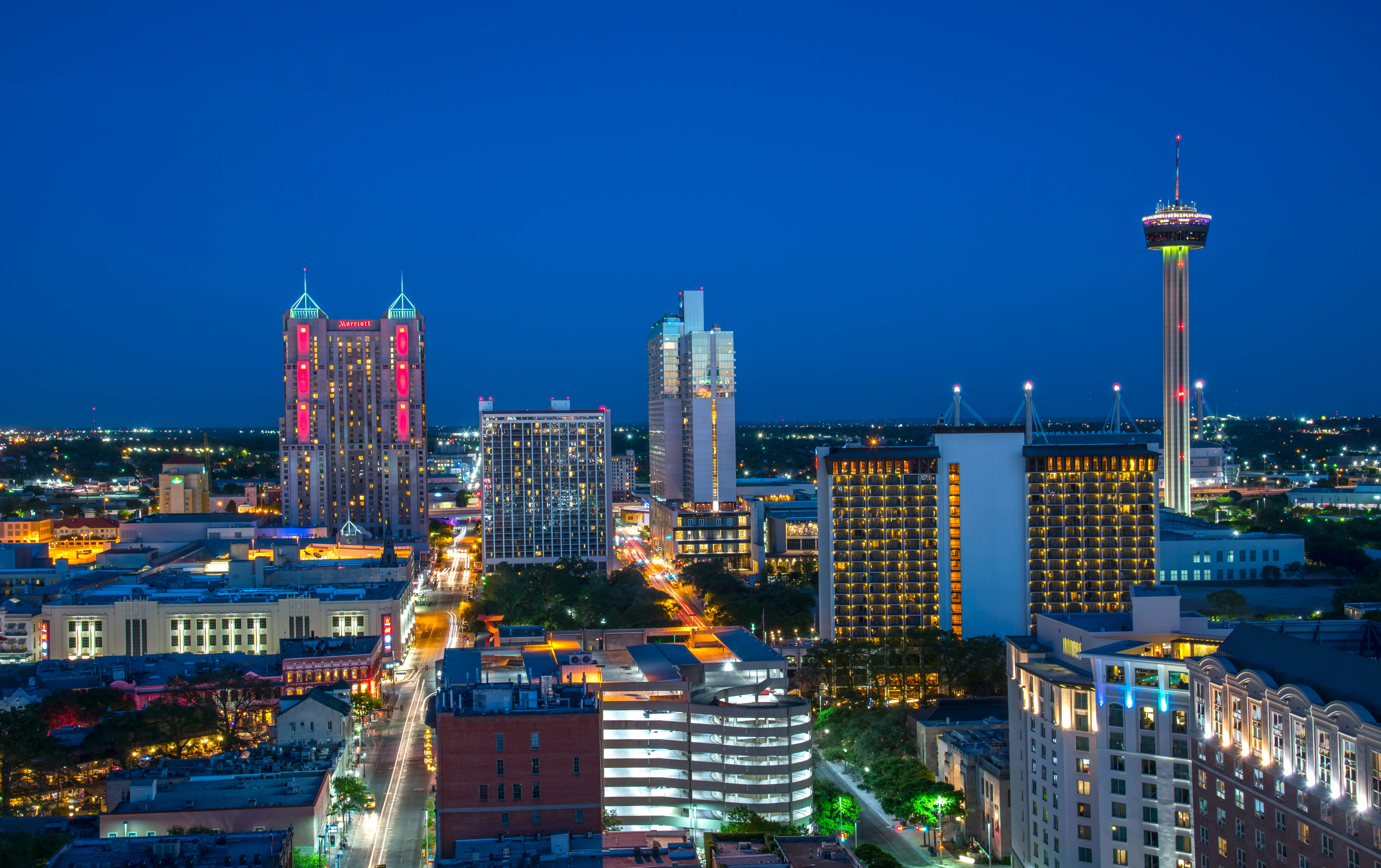 Downtown San Antonio skyline glows at dusk with the Tower of the Americas rising above illuminated streets.