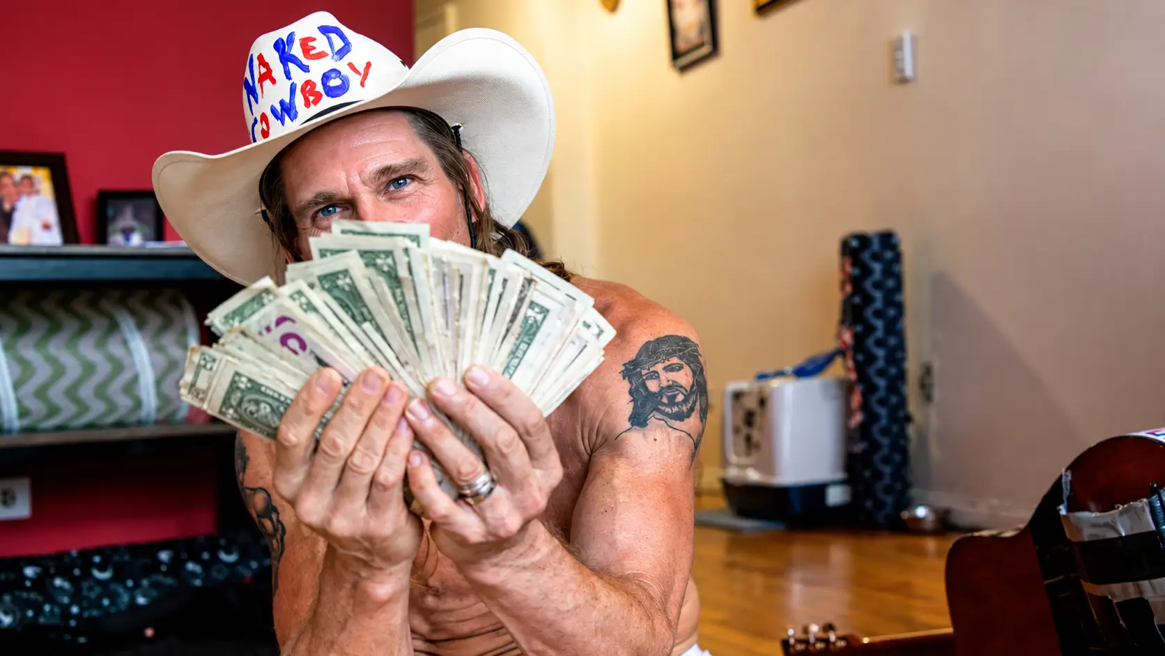 The Naked Cowboy holds up tips he made from working in Times Square.