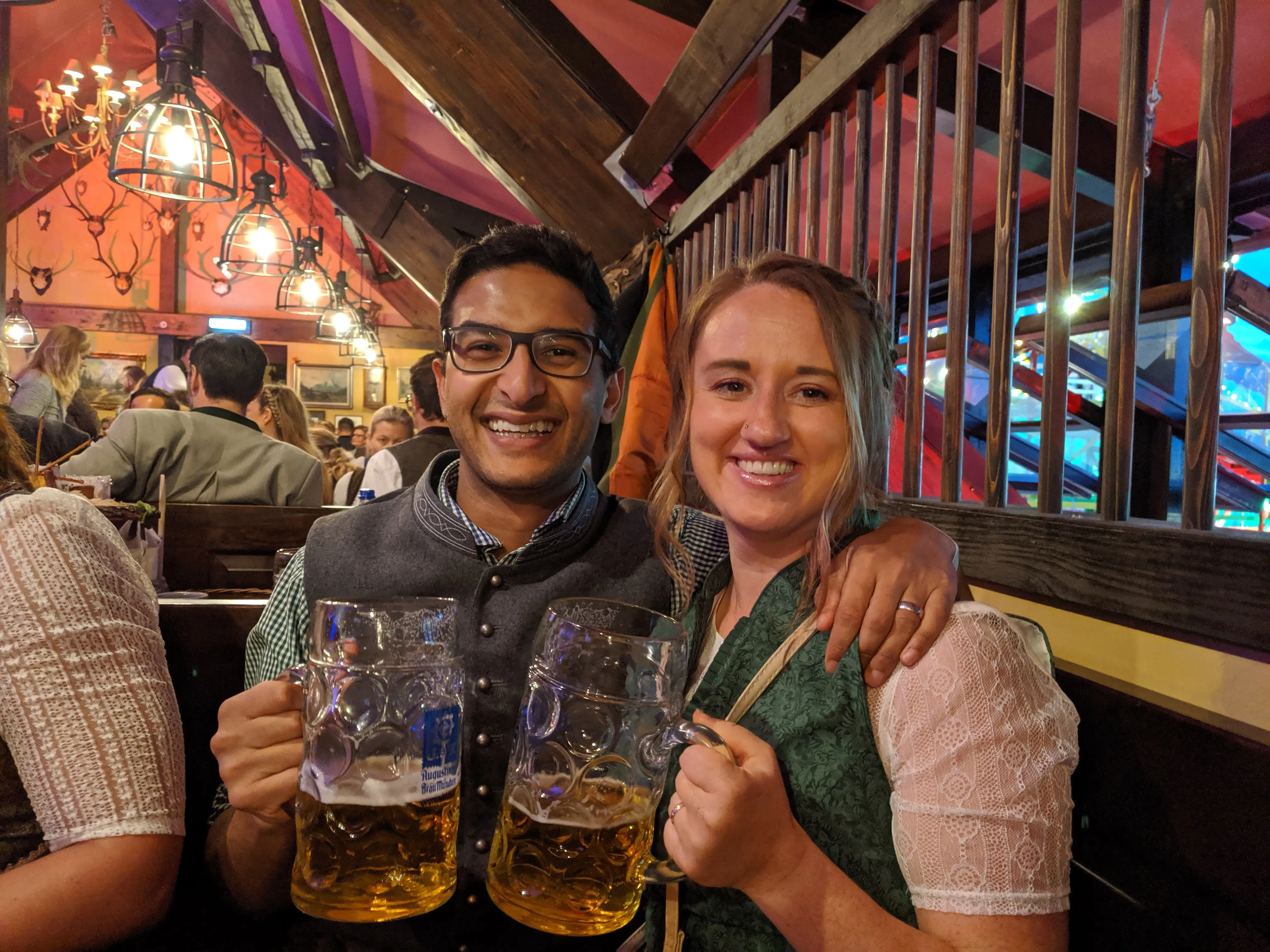 Man and woman with beer steins at Oktoberfest, smiling