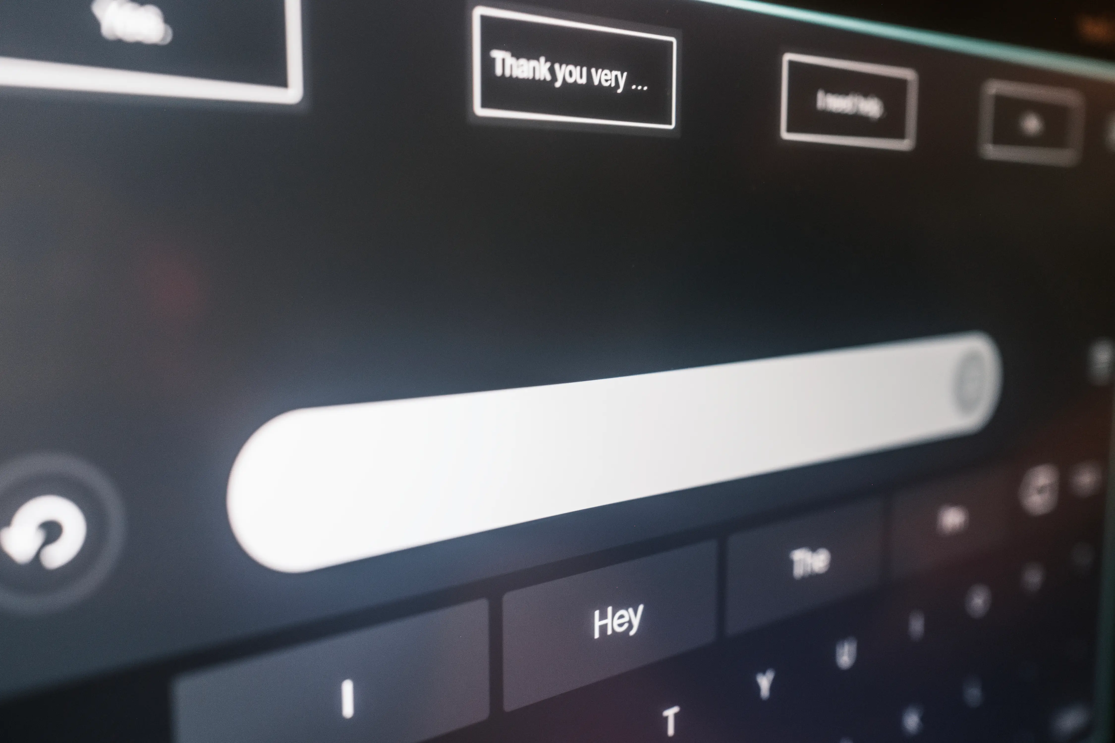 Close-up of a touchscreen text input interface with suggested phrases and an on-screen keyboard in low light.