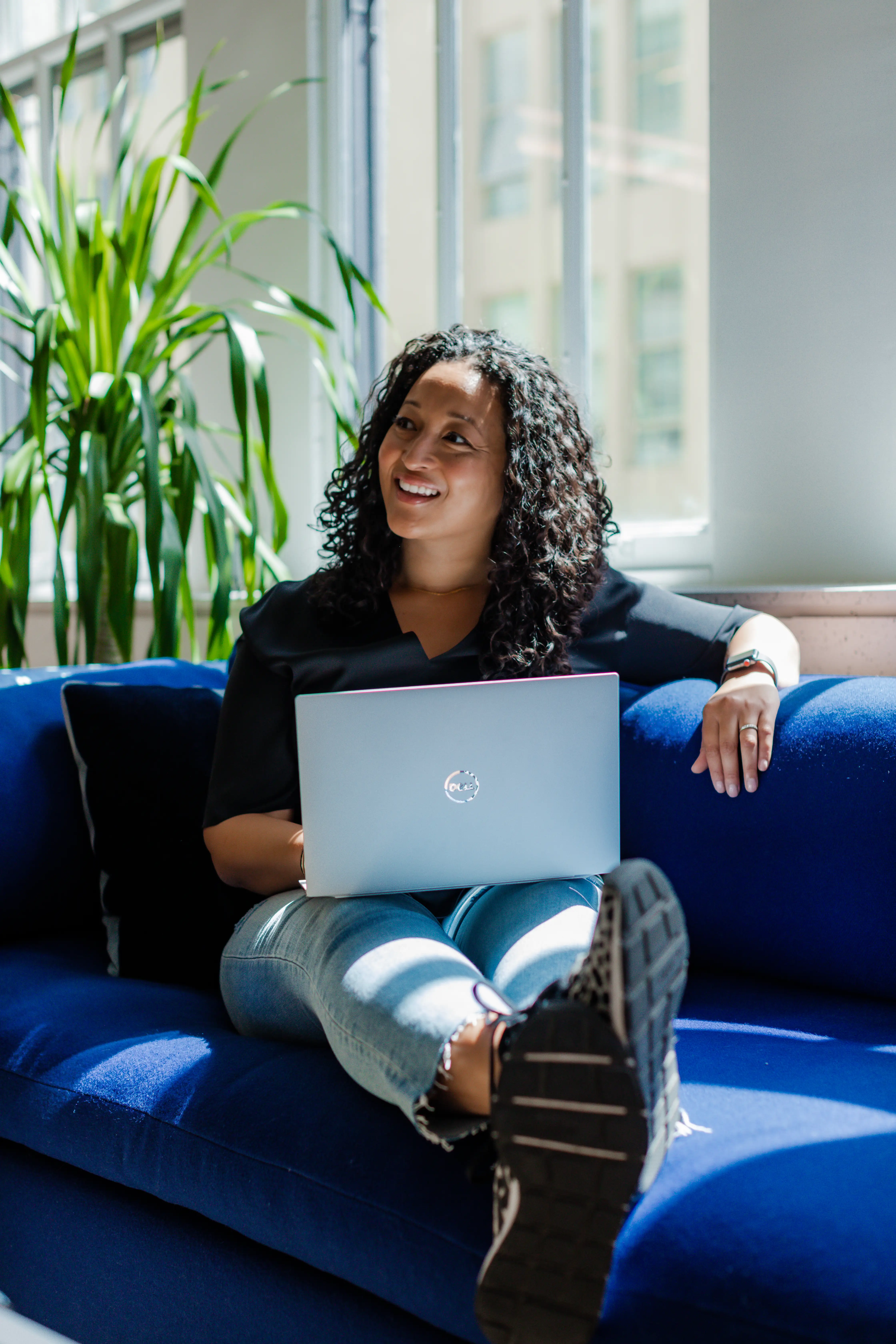 Denise Woodard, sitting on ablue couch with a laptop.