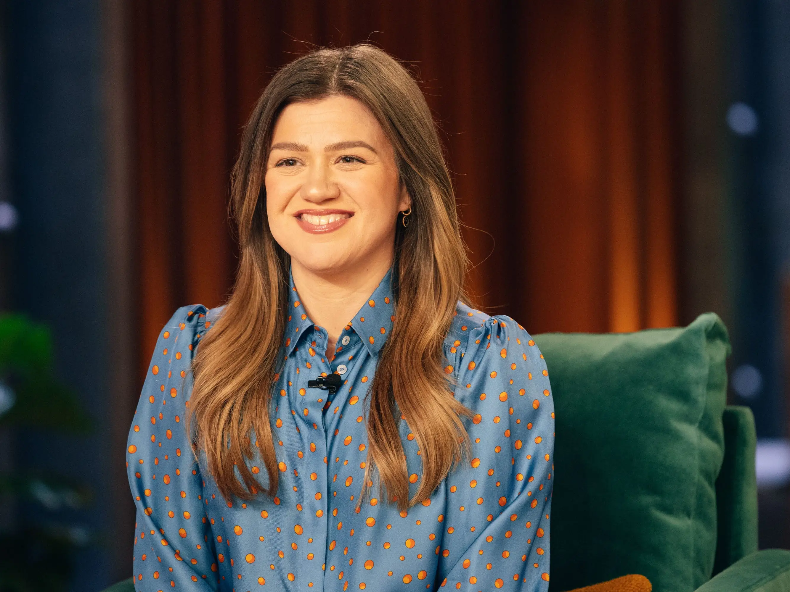 Kelly Clarkson in a blue and orange polka dot top on The Kelly ClarksonShow.