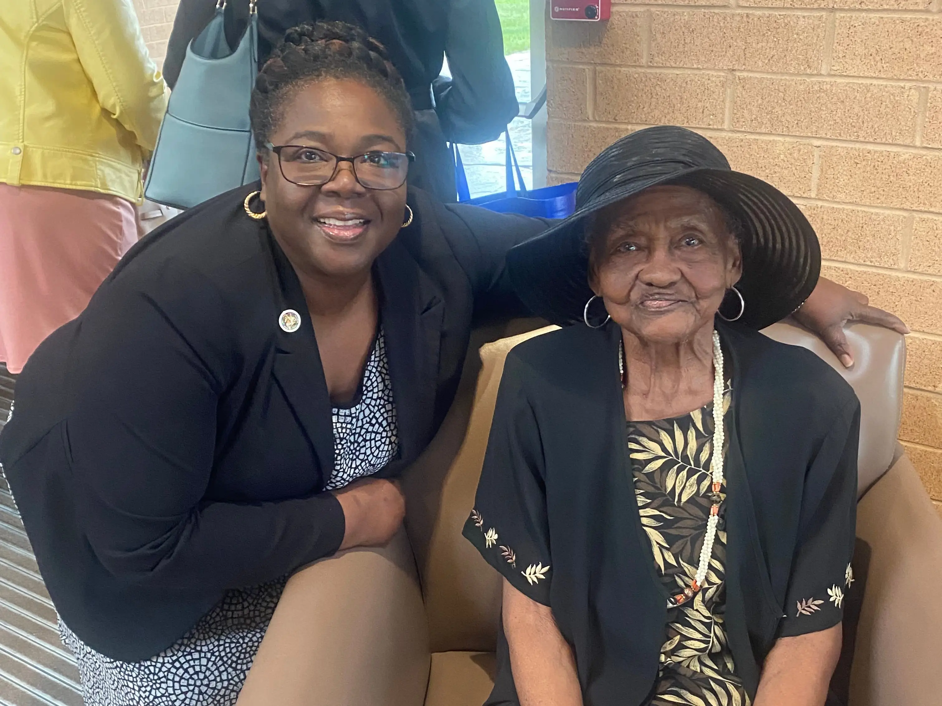 A mother and daughter, with the mom sitting in a chair.