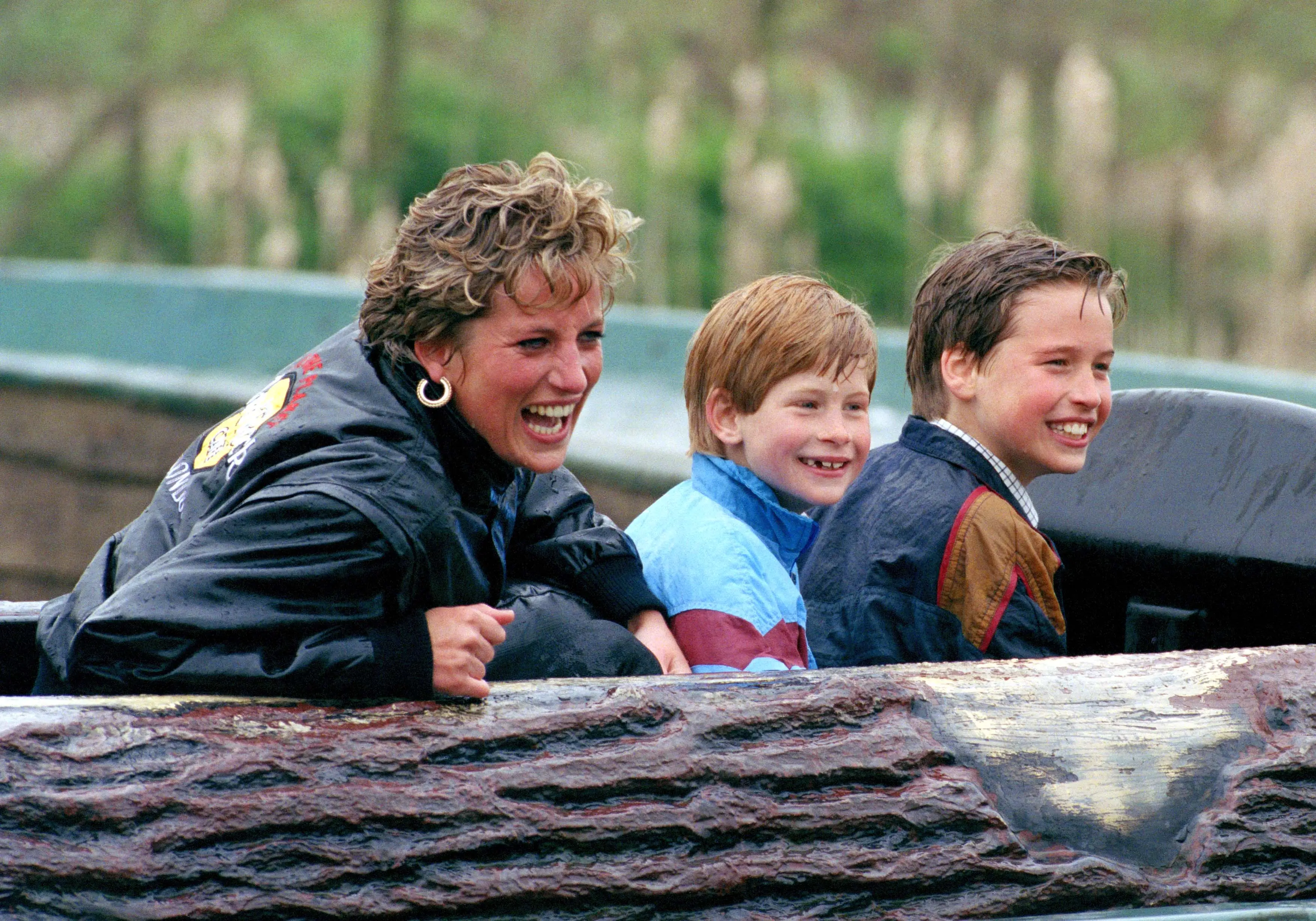 Princess Diana sits with Princes Harry and William on a log flume ride at an amusement park.