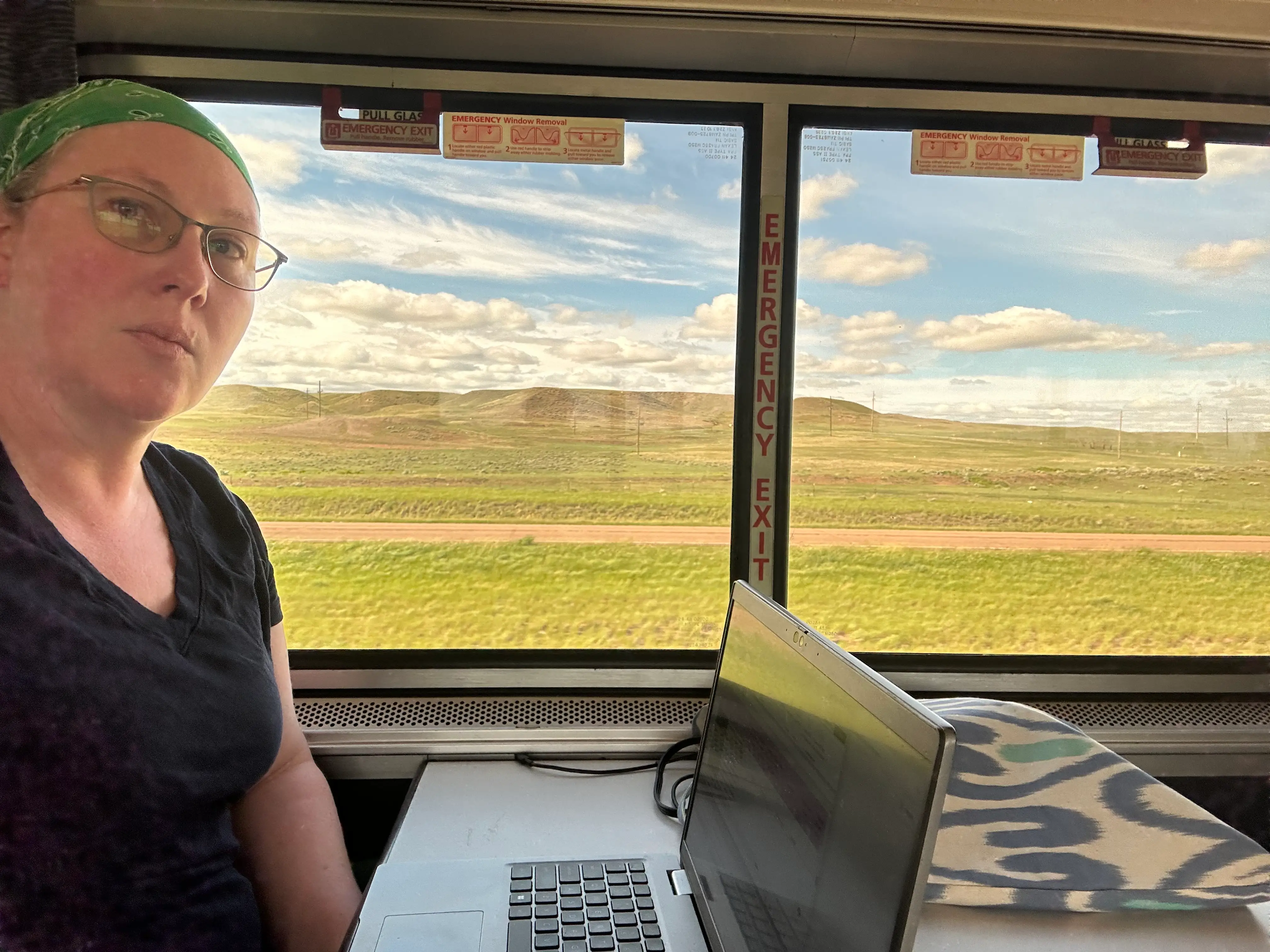 The writer is working on her laptop while riding an Amtrak train.