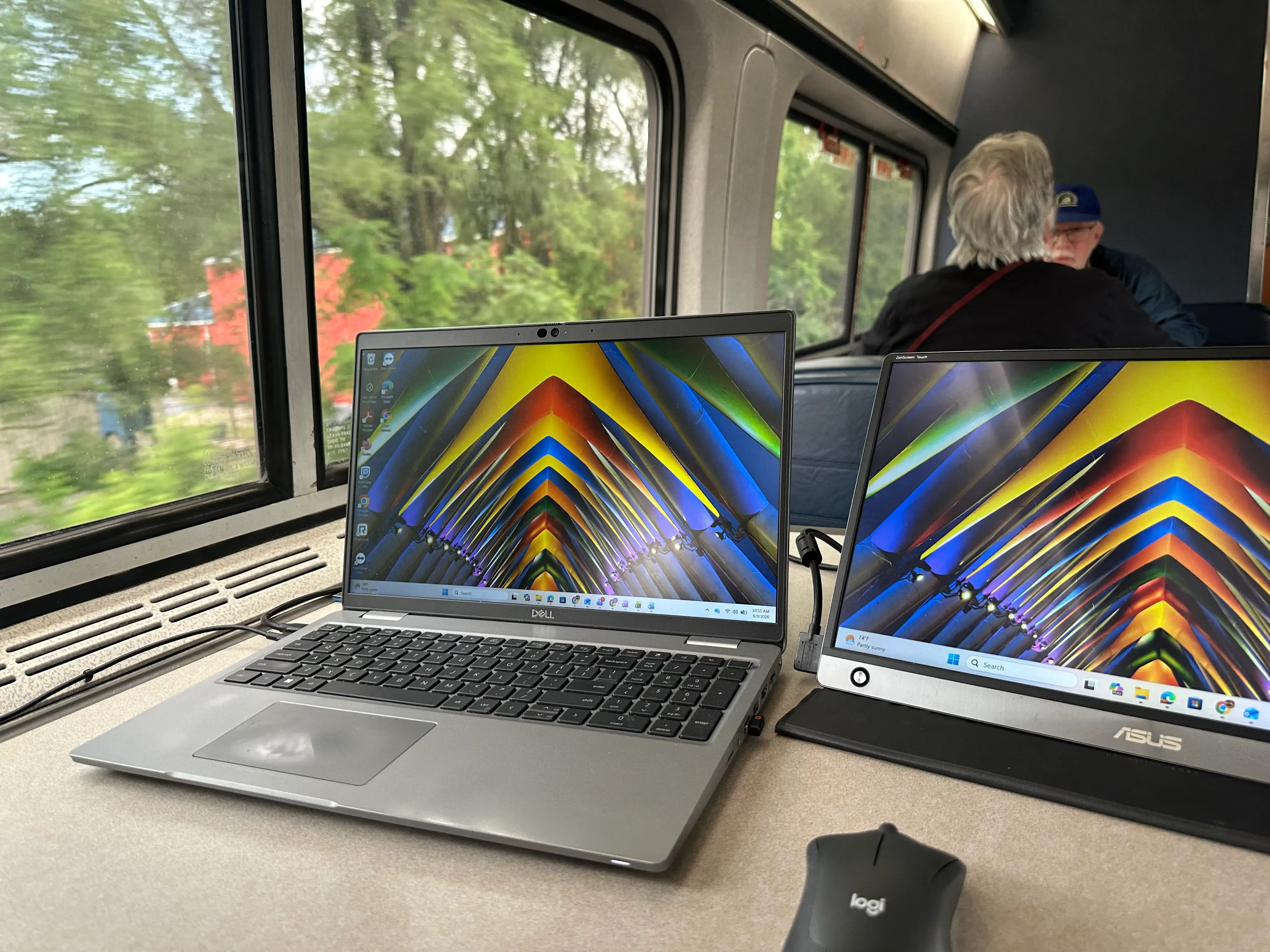 The writer's laptop and second screen are sitting on a table on an Amtrak train.