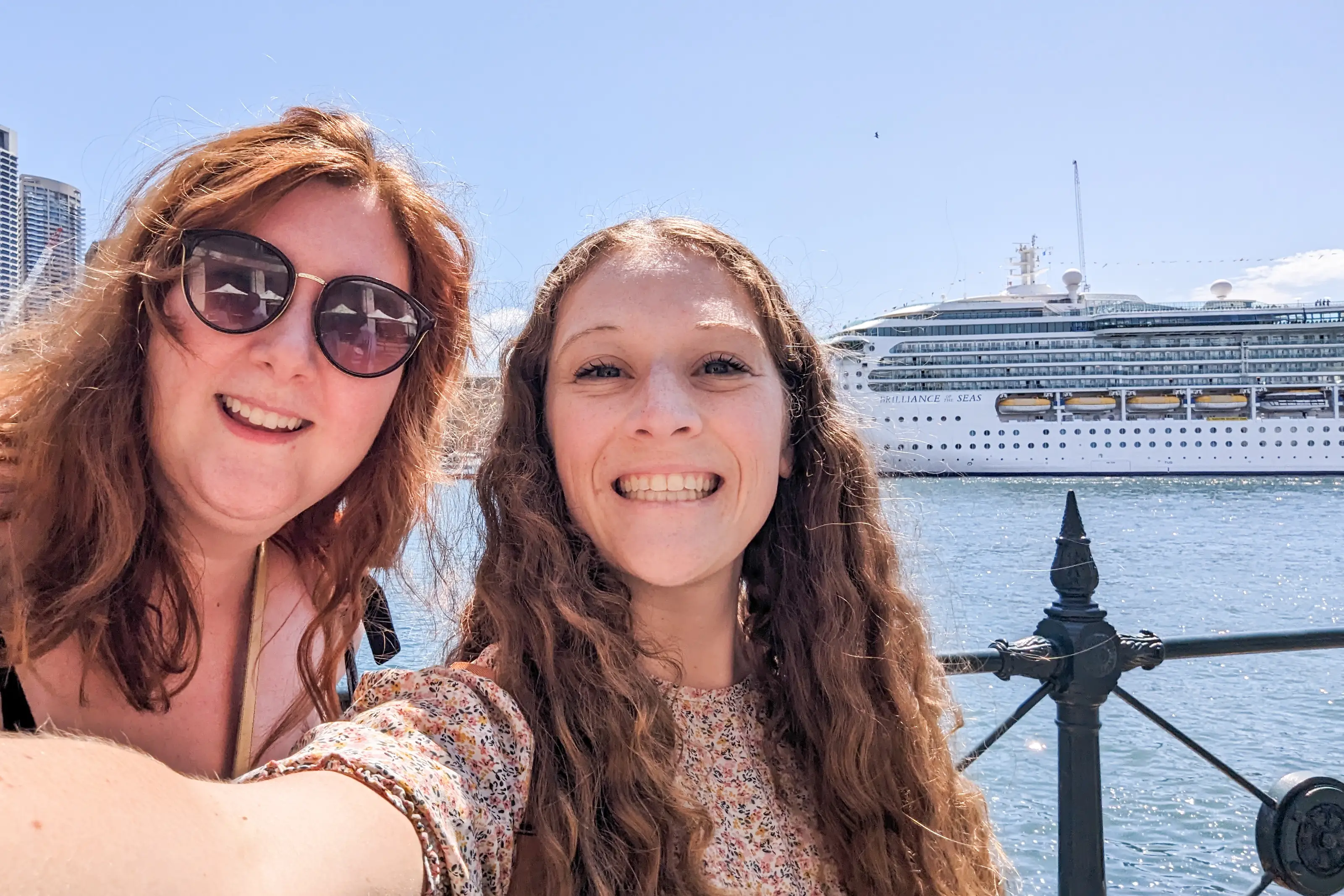 Two women smiling in selfie with cruise ship in background