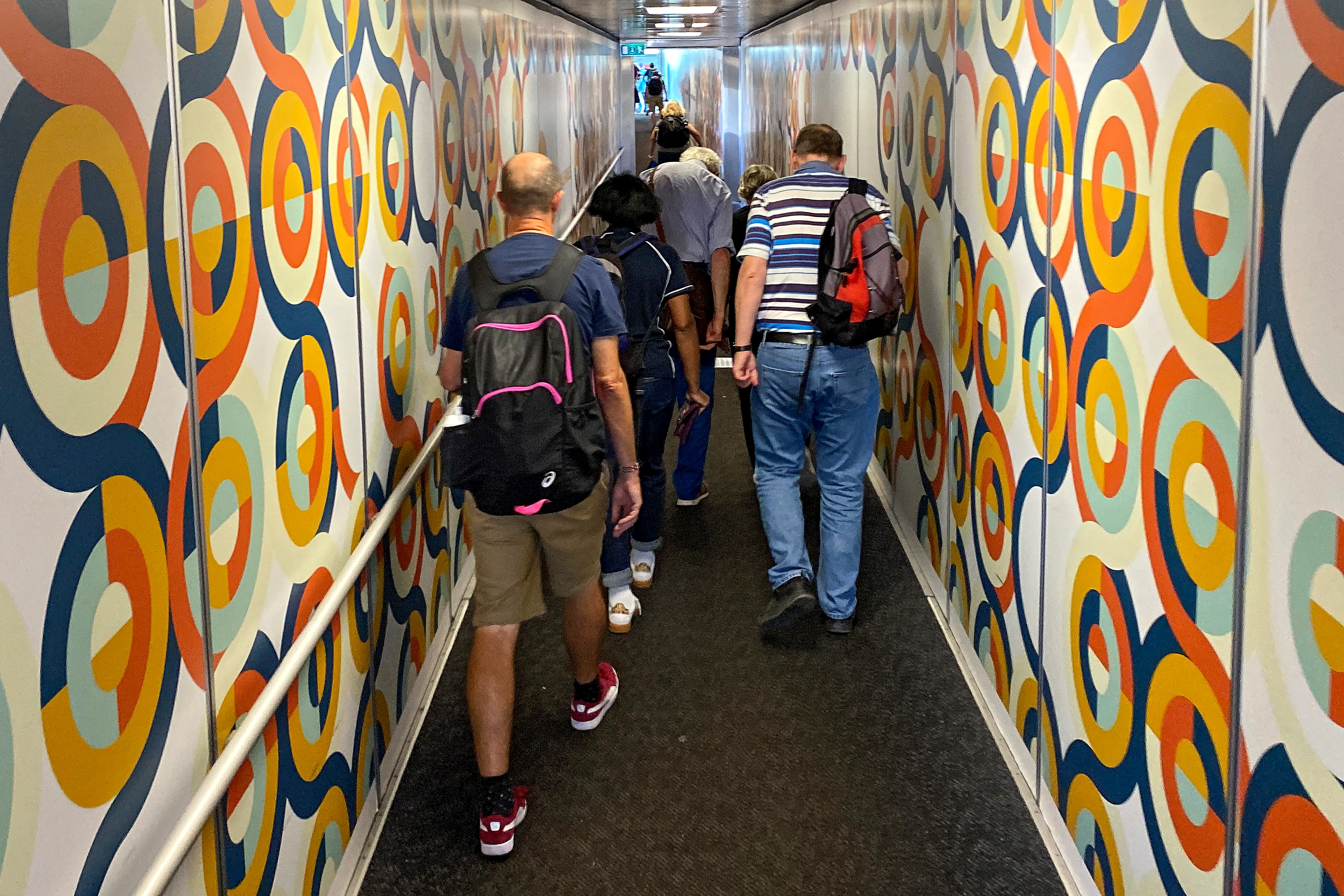 Passengers walk on a jet bridge