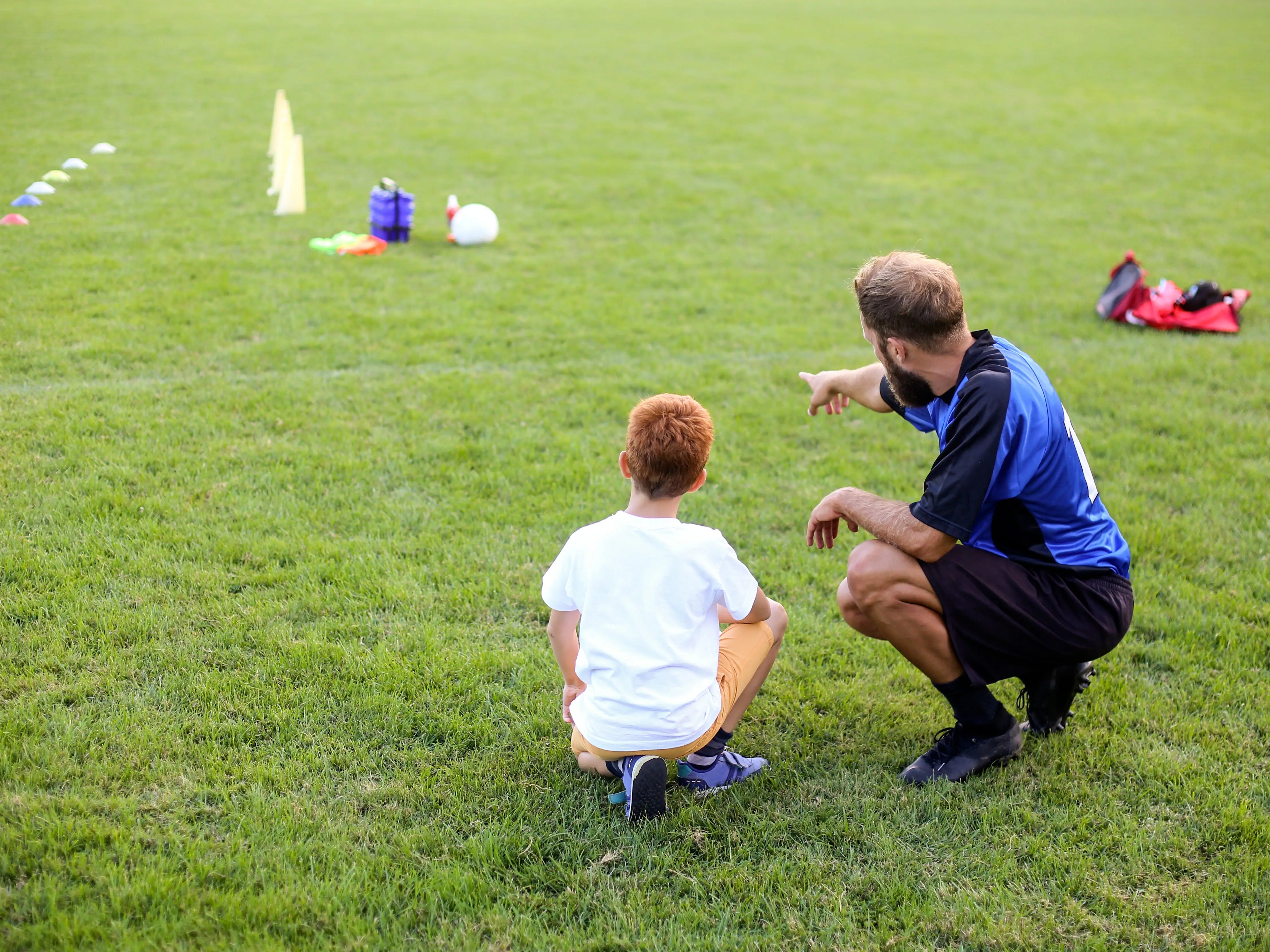 dad coaching a boy on a soccer field