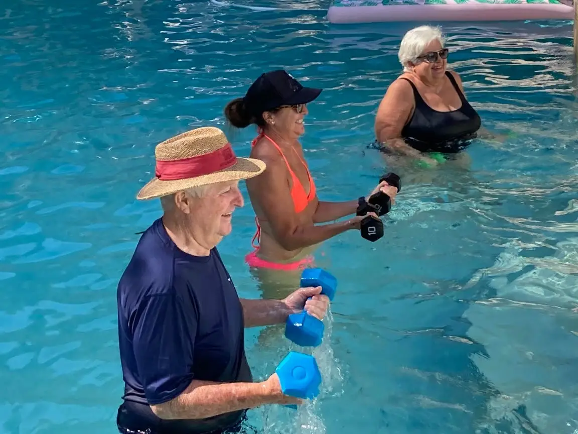 Blakes grandfather, mother, and grandmother lifting weights in a pool.