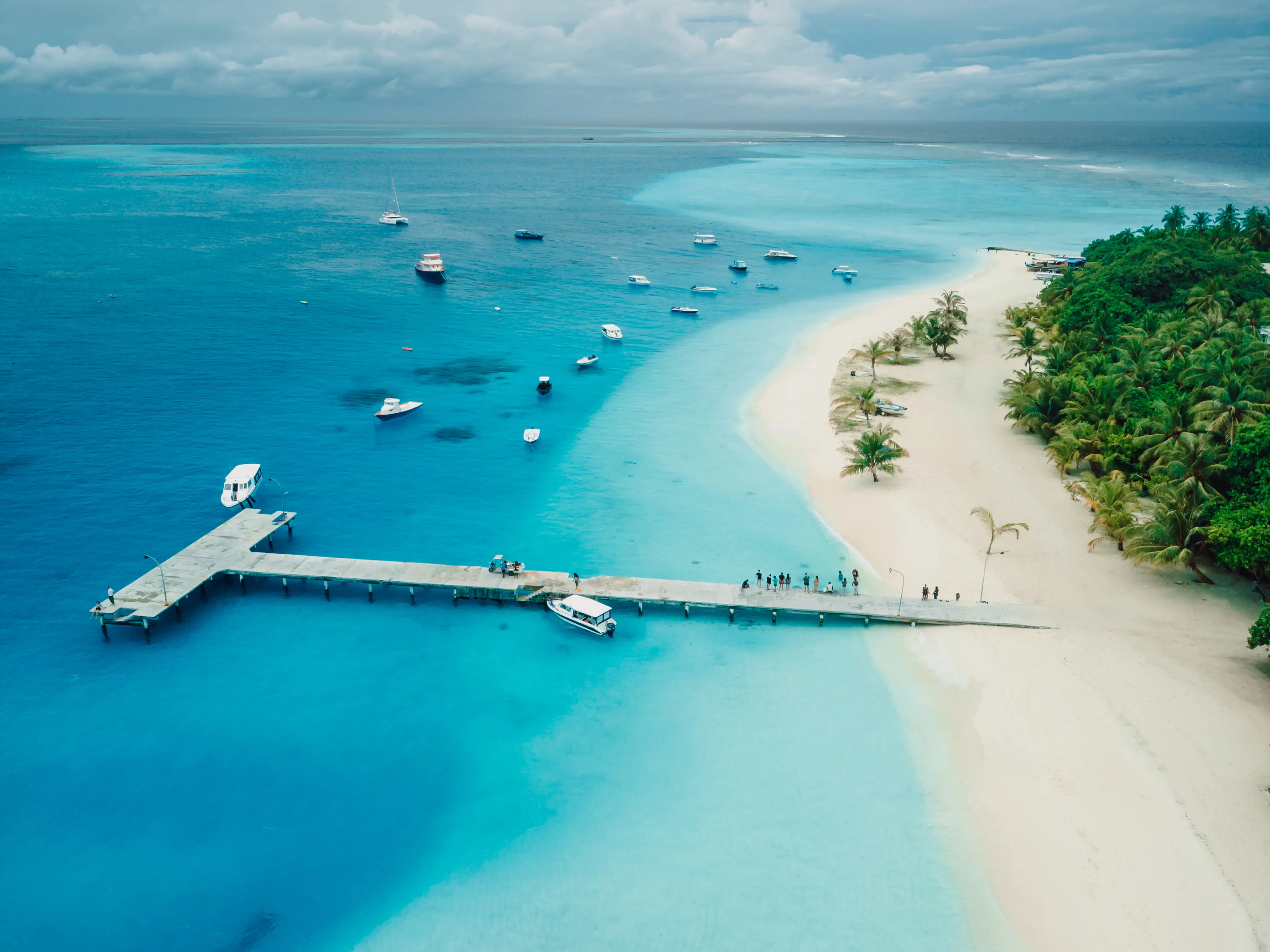 Maldives tropical beach with pier and touristic boats on Fulidhoo island. Travel vacation concept, drone shot stock photo