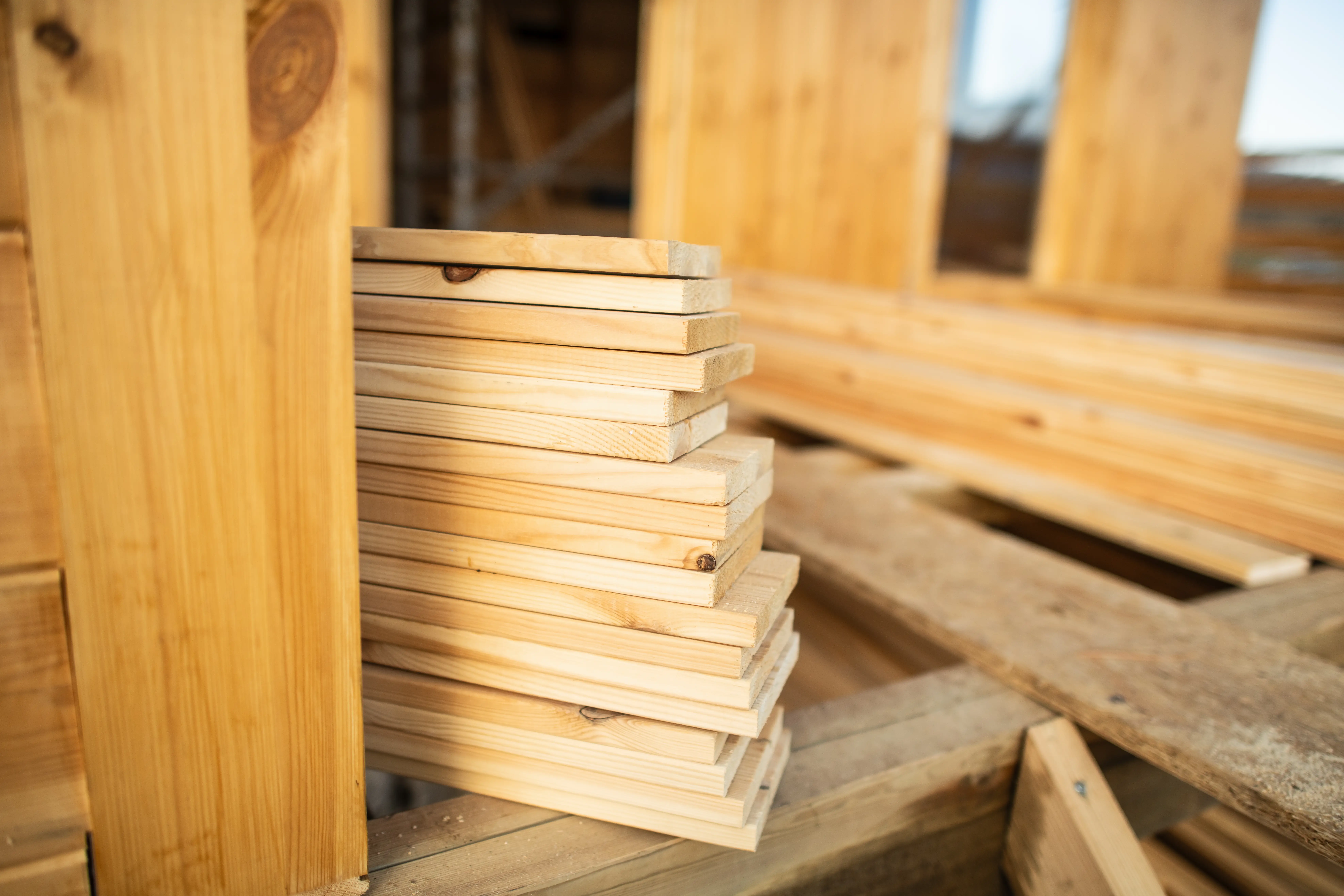 Stacked wooden boards and framing lumber rest on a work surface.