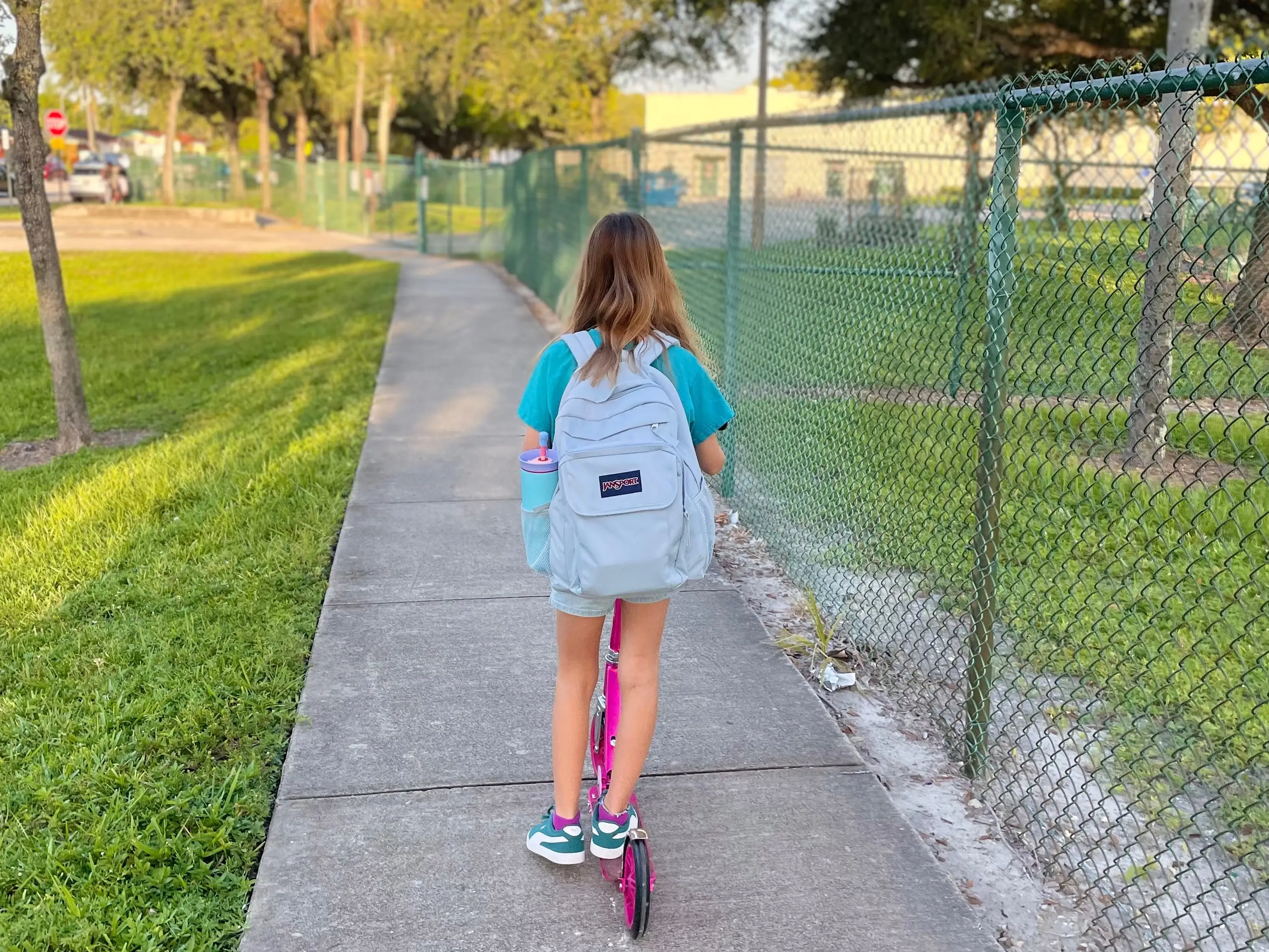 the author's daughter heading to school on a scooter