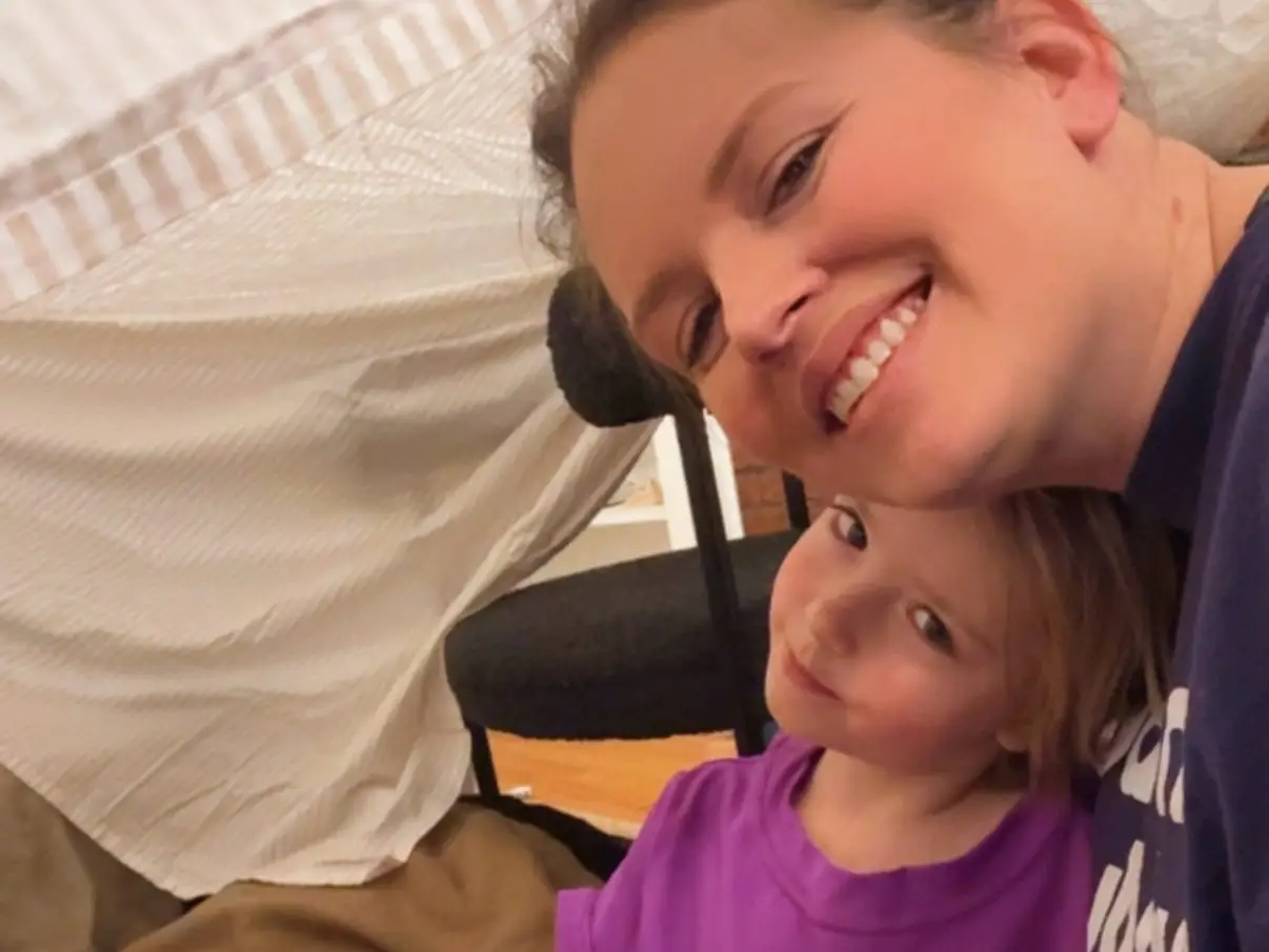 The writer posing for a selfie with her niece under a blanket fort.