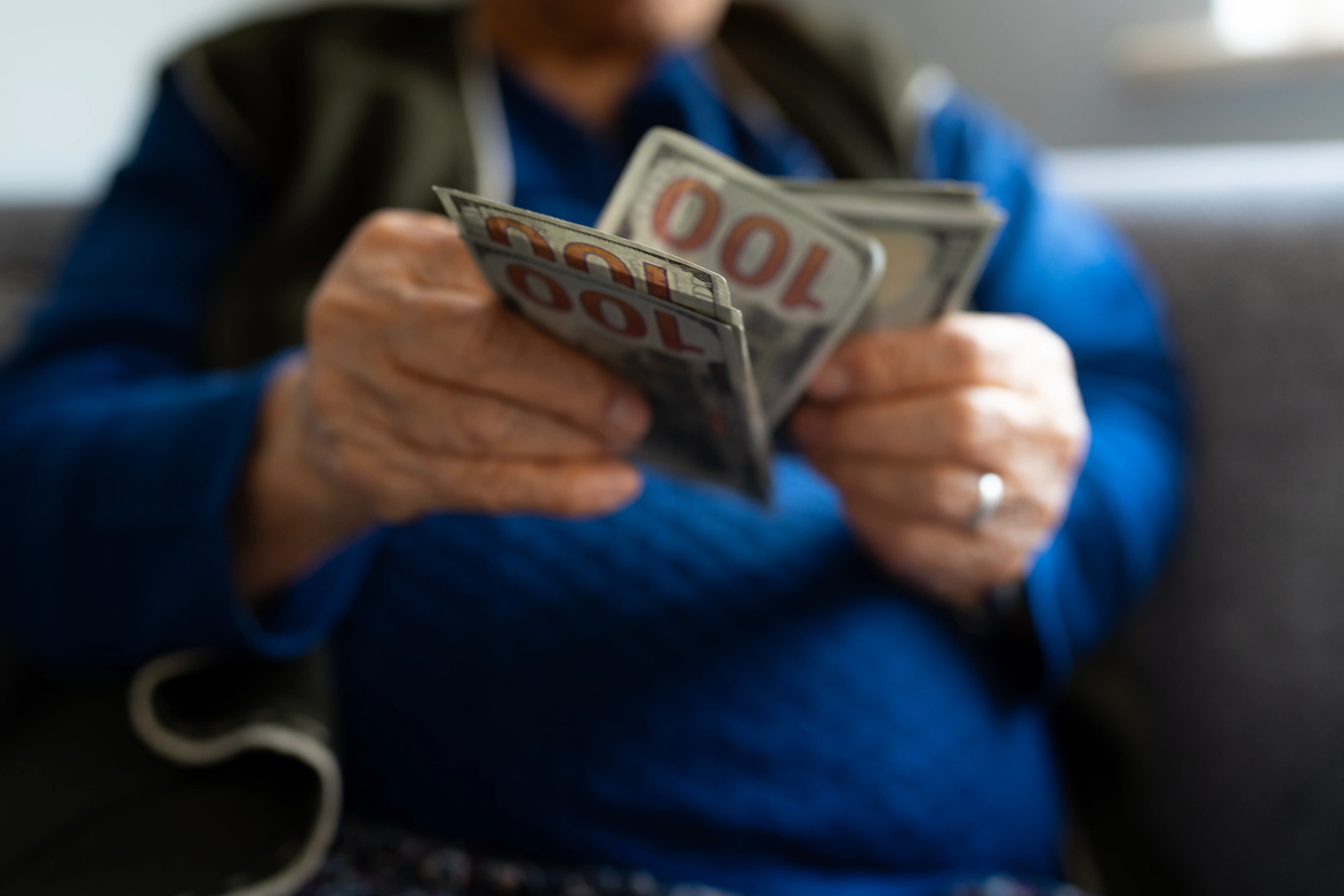 Senior woman's hands holding and counting hundred dollar bills