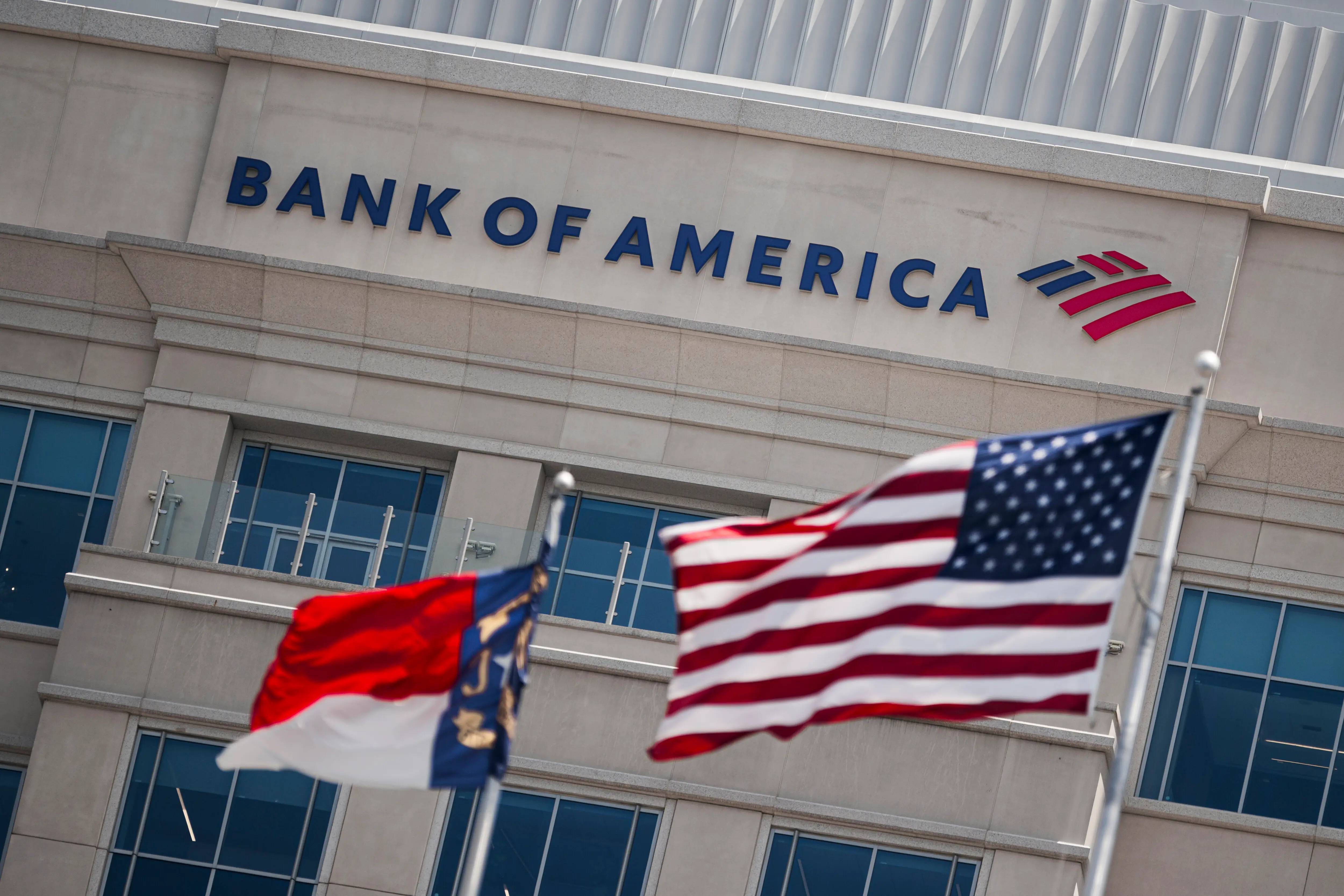 A detail shot shows the Bank of America Tower at Legacy Union as the USA flag waves in the foreground, flanked by the flag of North Carolina at left.