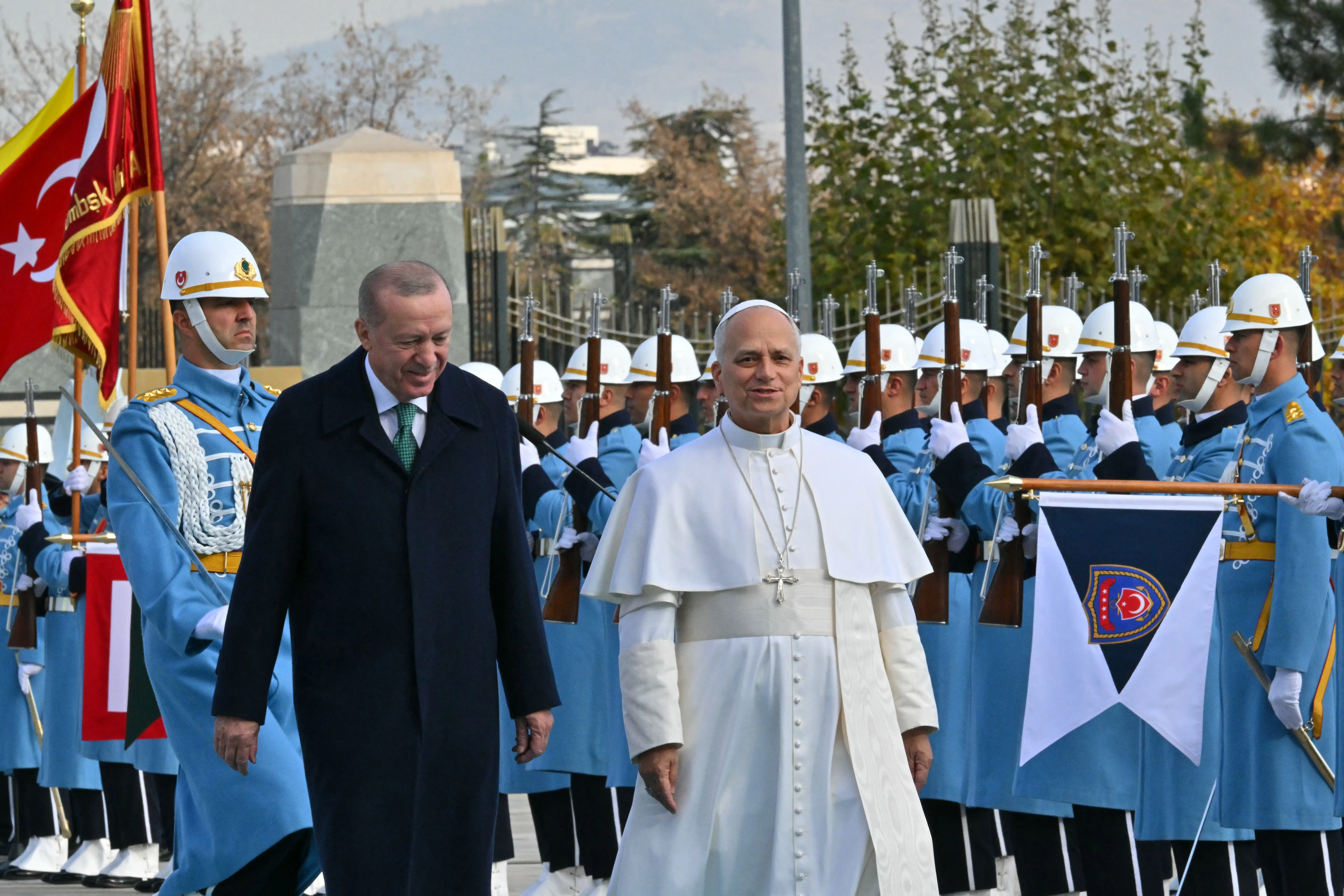 Recep Tayyip Erdoğan walks beside Pope Leo XIV during a ceremonial military honor guard with Turkish flags.