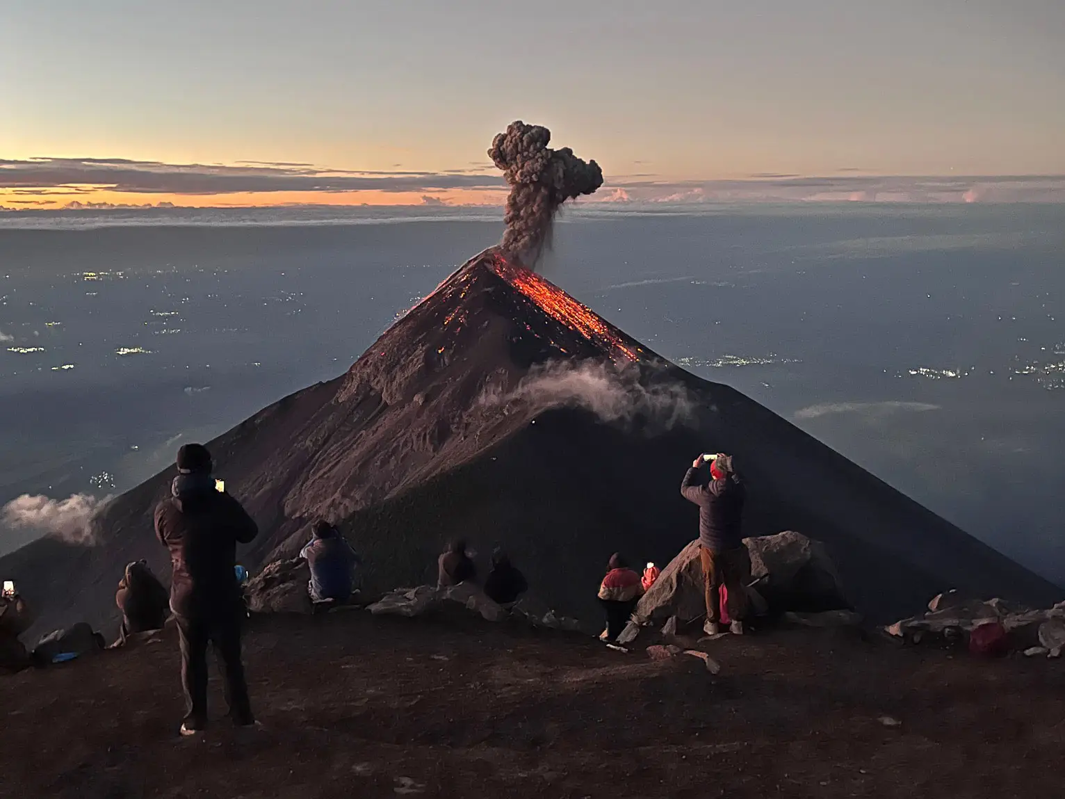 The view of an erupting volcano from the top of a neighboring volcano.