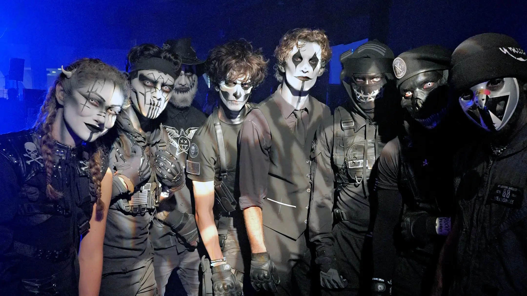 seven costumed people in black with face paint