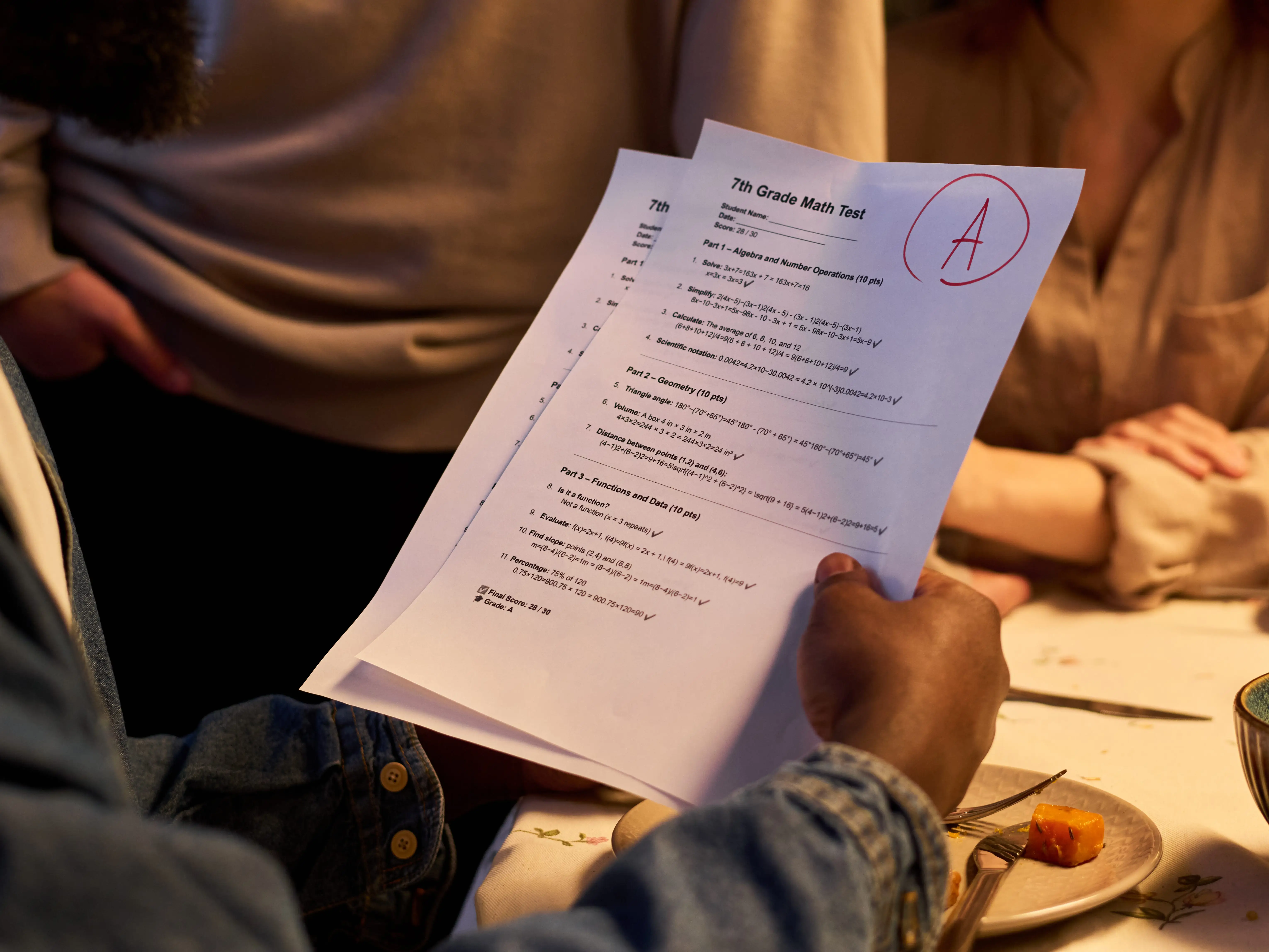 African American father holding teenager math test with top grade while family gathering around table, showing academic success and parental support. Ideal for education campaigns