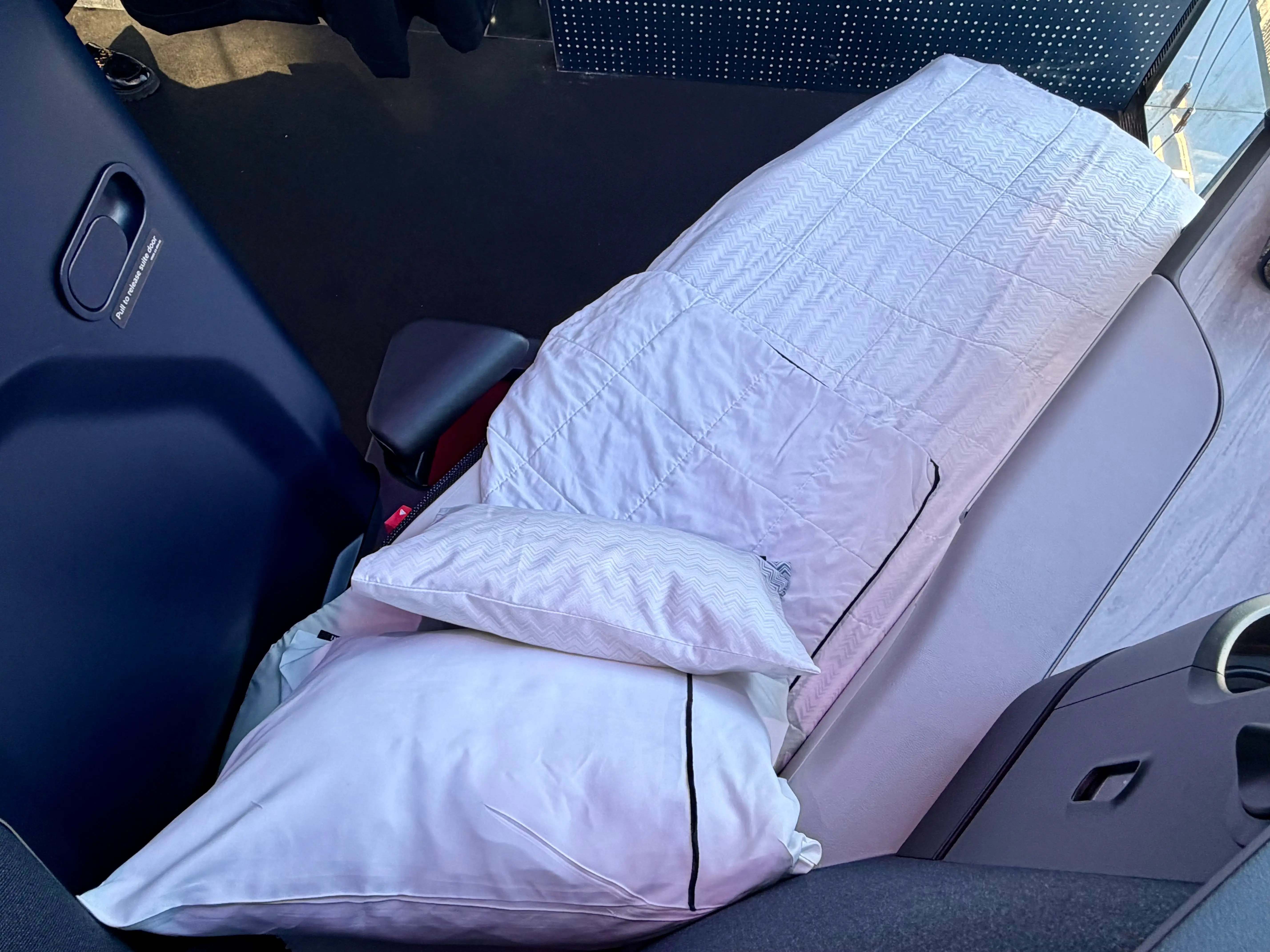 The lie-flat bed on Delta with white linens.