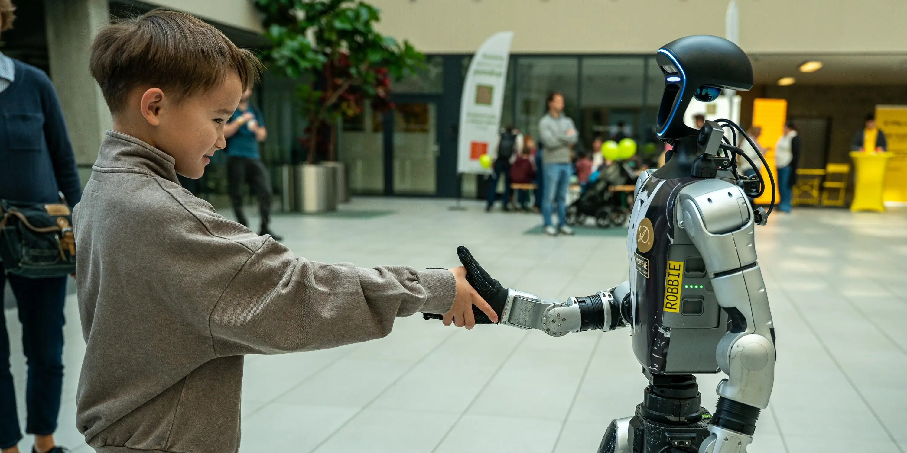 A boy shakes hands with a humanoid robot.