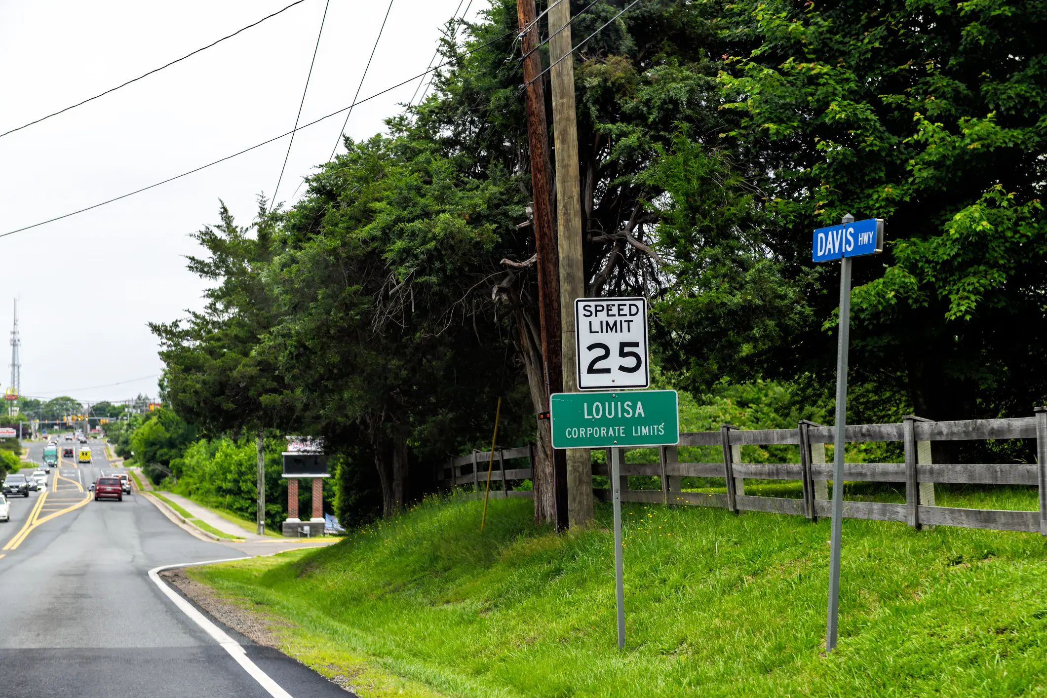 Roadside signs mark Davis Hwy and Louisa corporate limits beside a 25 mph speed limit sign.