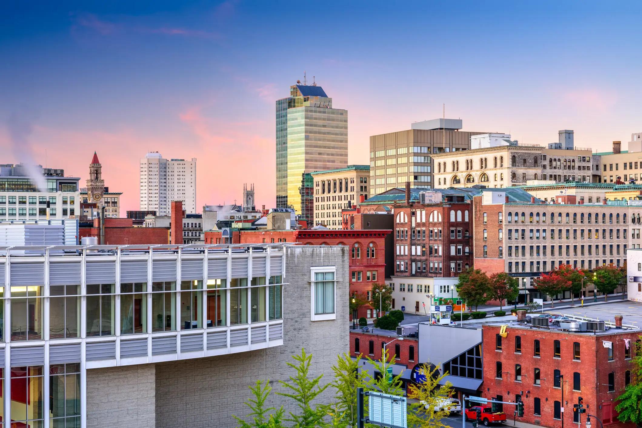 Downtown Worcester skyline at sunset with brick buildings, a clock tower, and modern high-rises.
