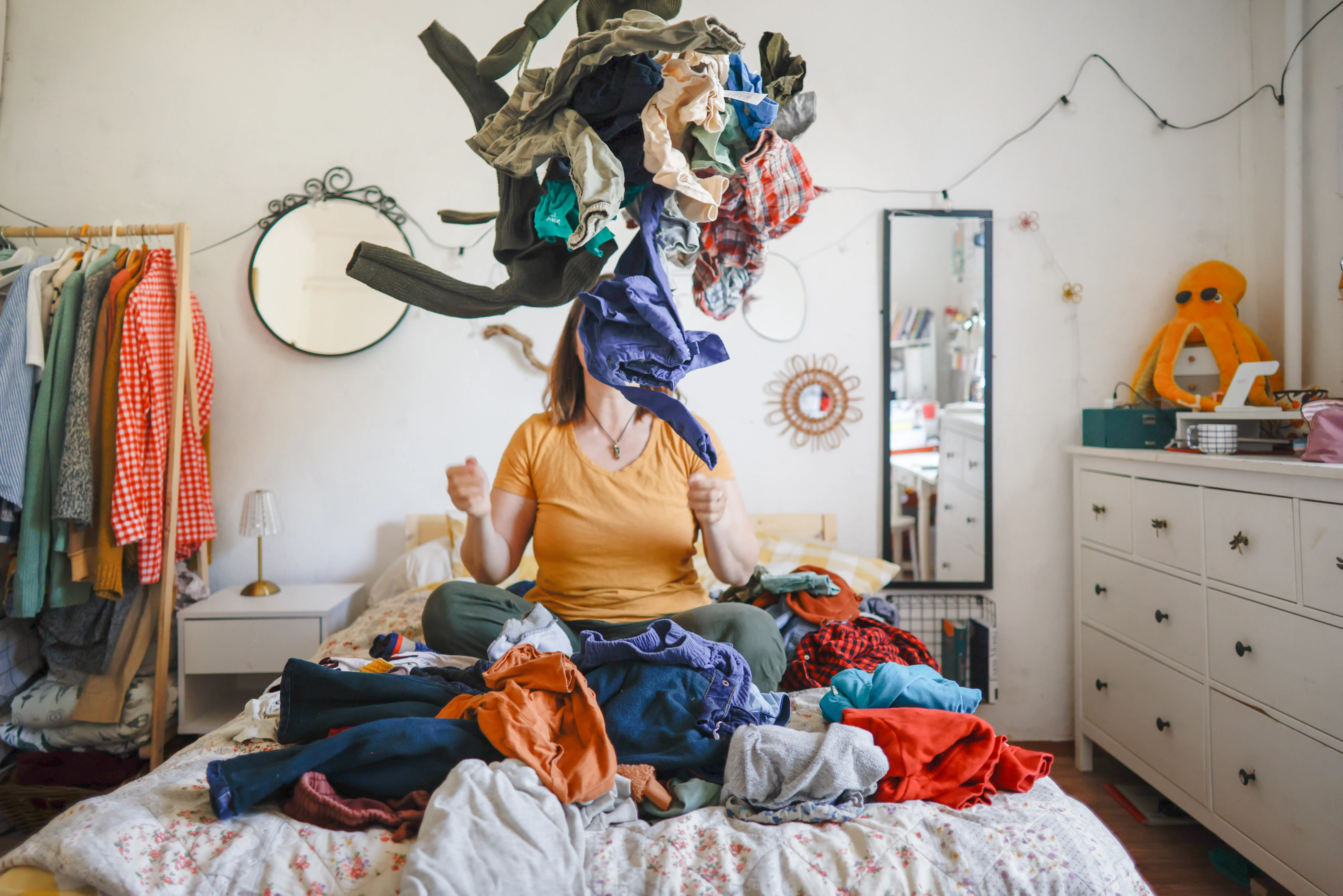 middle-aged woman, a mother, on the bed in the bedroom in a pile of laundry, concept of being overwhelmed by household chores, the woman is not visible among the pile of laundry,