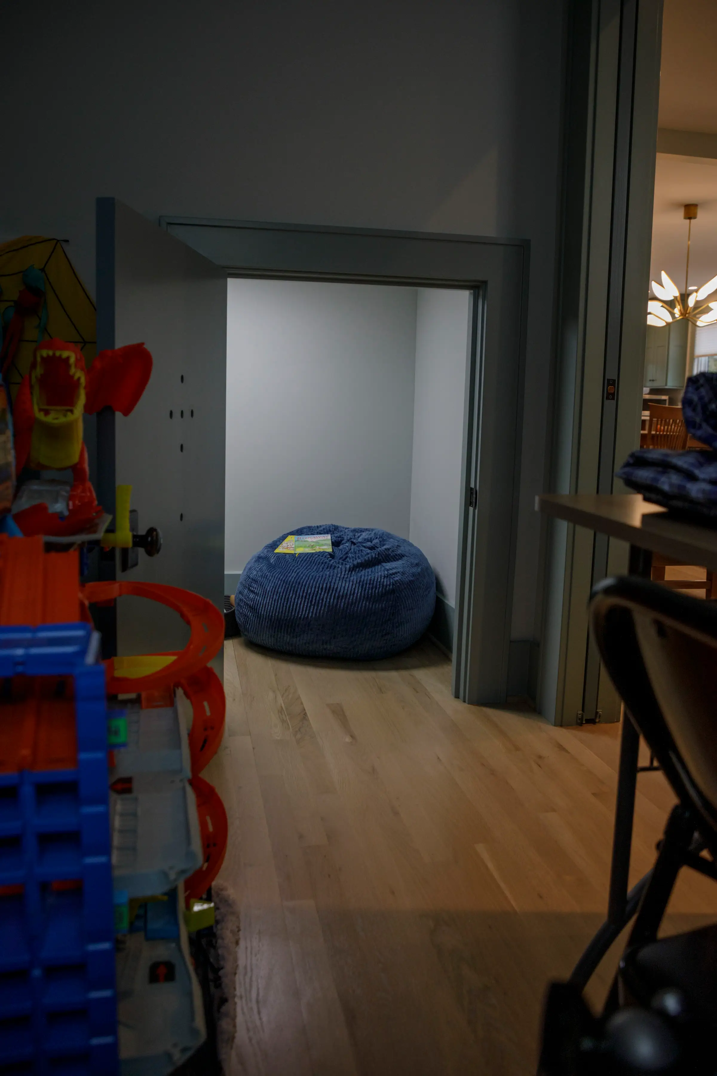Blue bean bag sits in a small alcove beside colorful toys in a modern interior hallway.