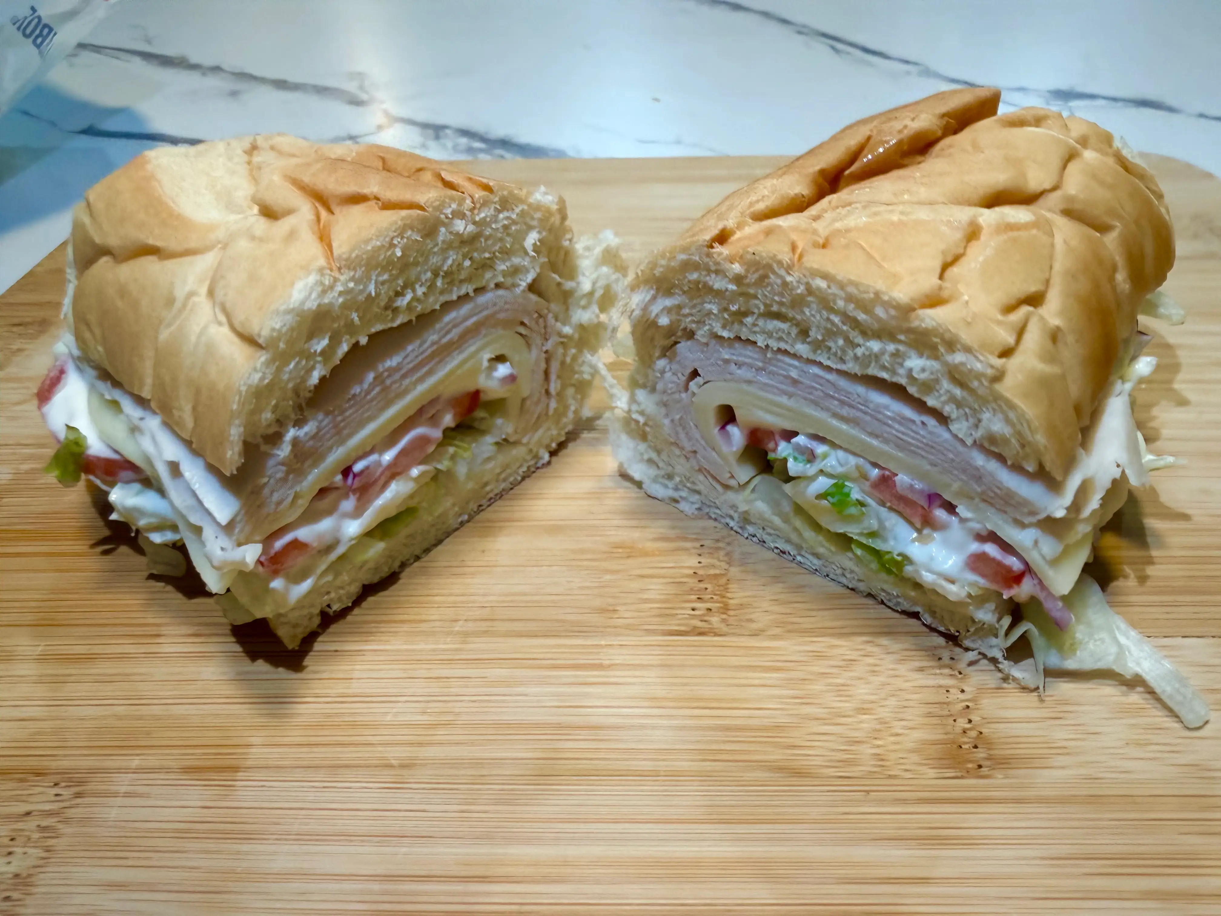 Subway sandwich cut in half with turkey, lettuce, tomato, mayo