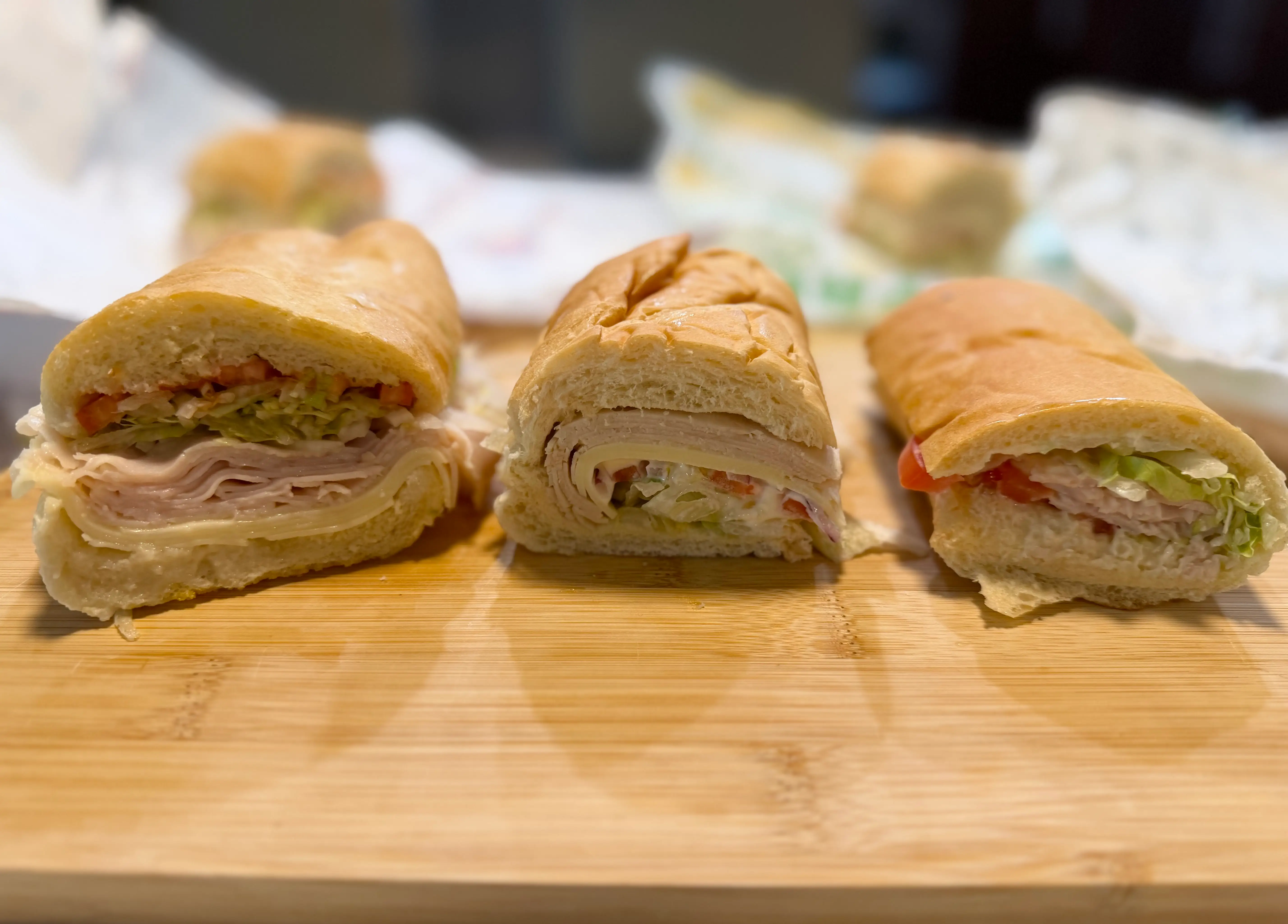 Turkey sandwiches from Jersey Mikes, Subway, and Jimmy John's side by side on cutting board
