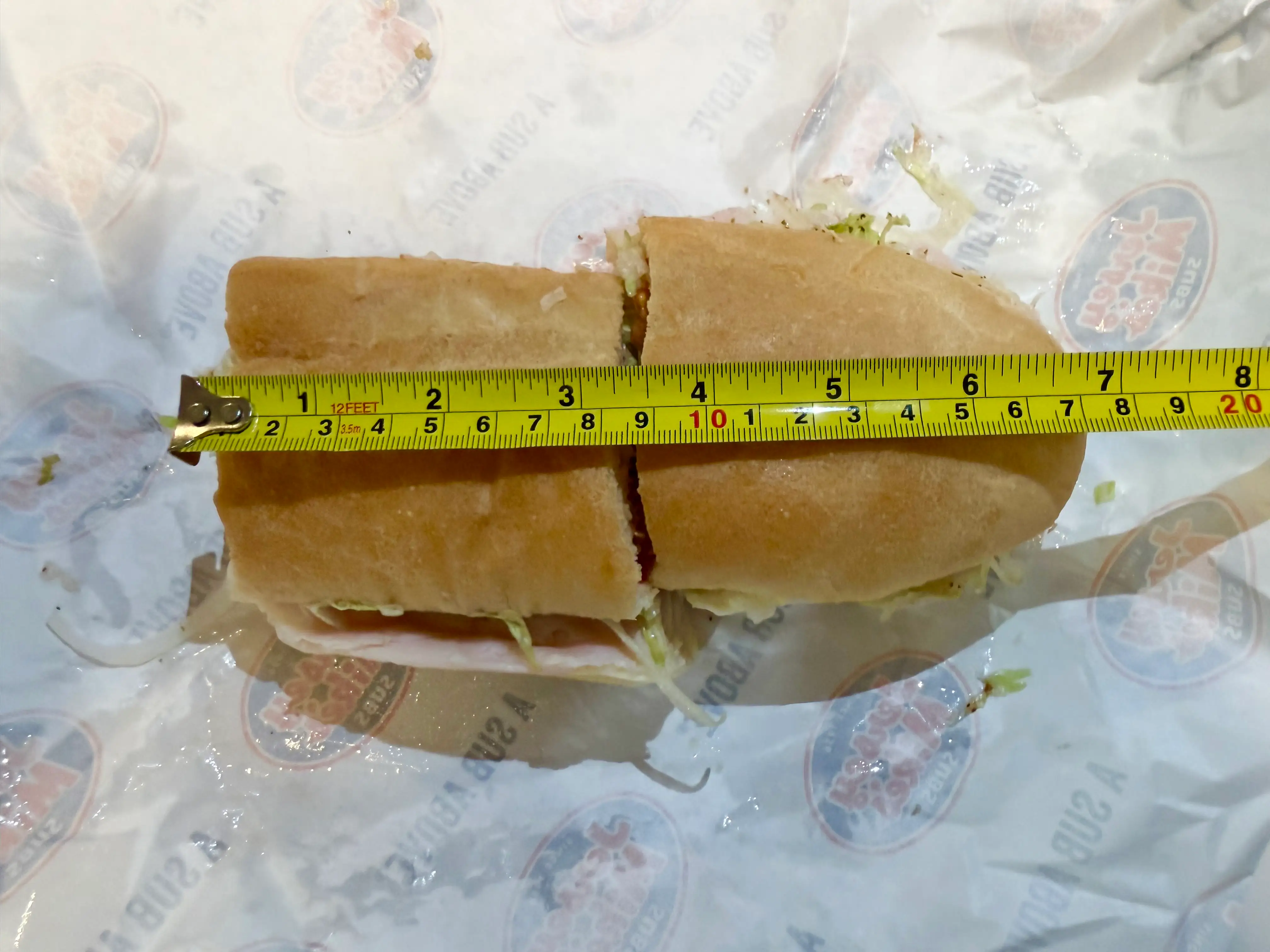 Sandwich from Jersey Mike's with tap measure on top of it measuring about 7 inches