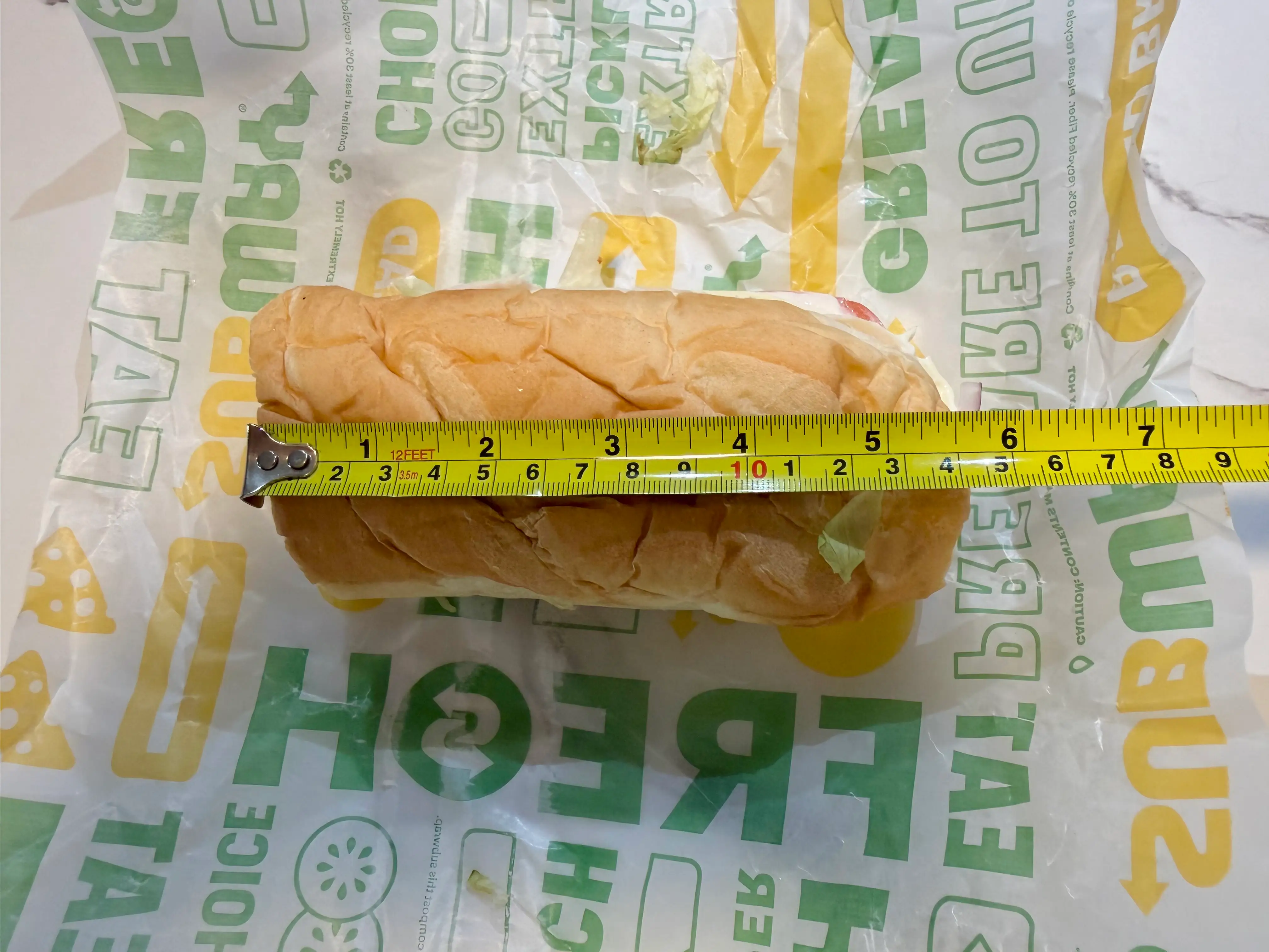 Subway sandwich with measuring tape on top showing 5.5 inches