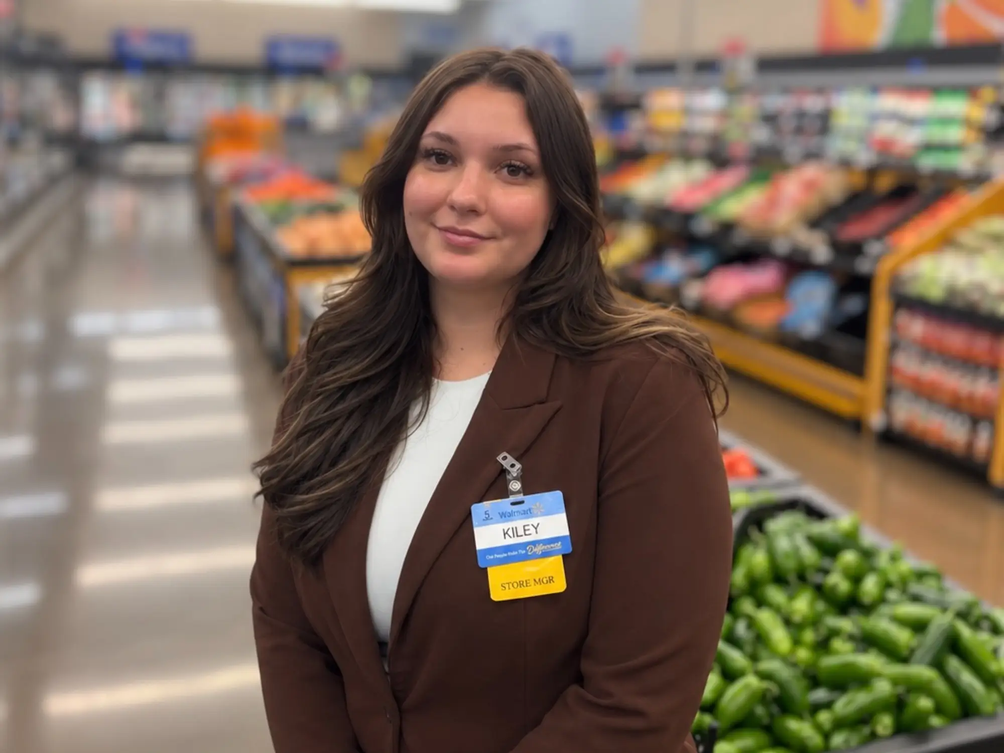 Kiley Pulley in the Walmart produce aisle wearing her name badge on a brown blazer.