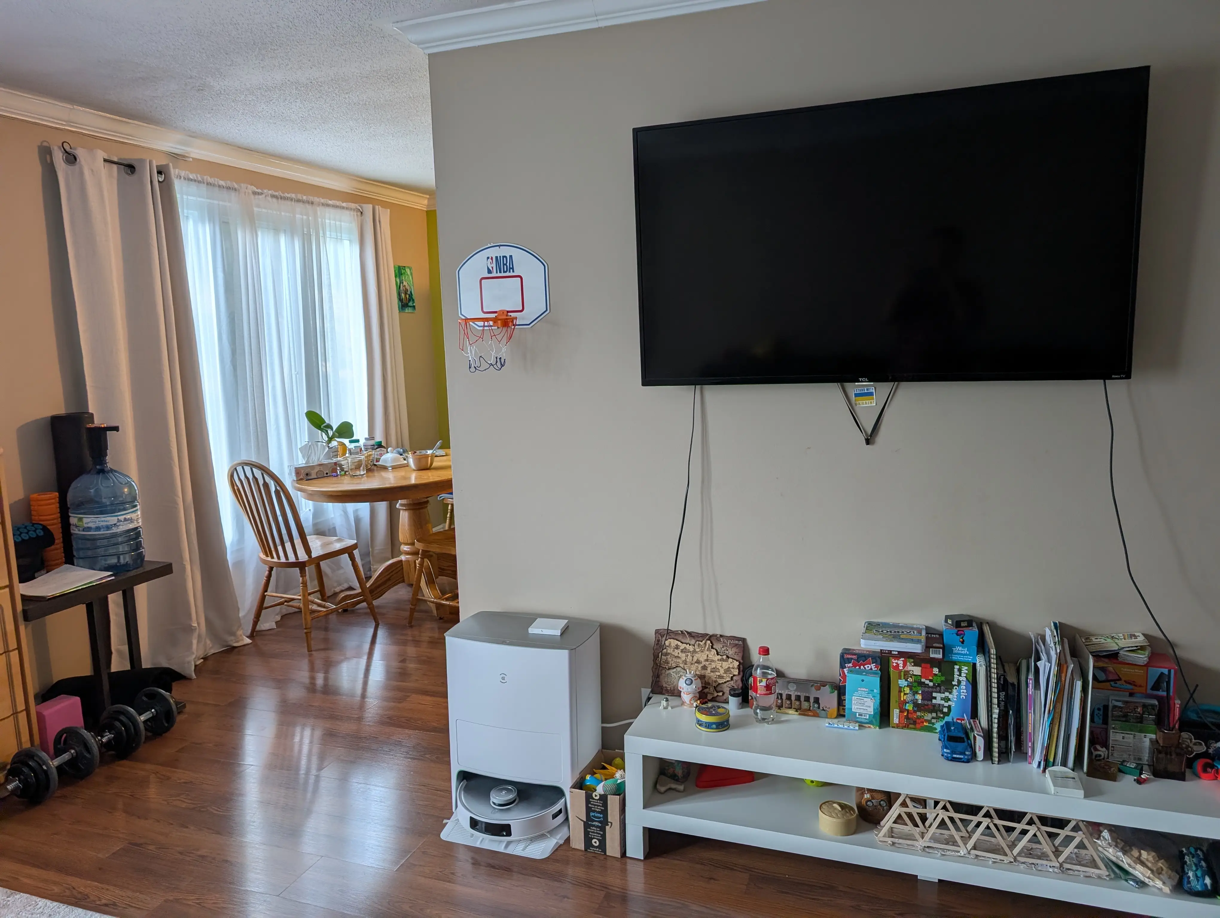 Living room area with view of dining room behind it, TV mounted on the wall