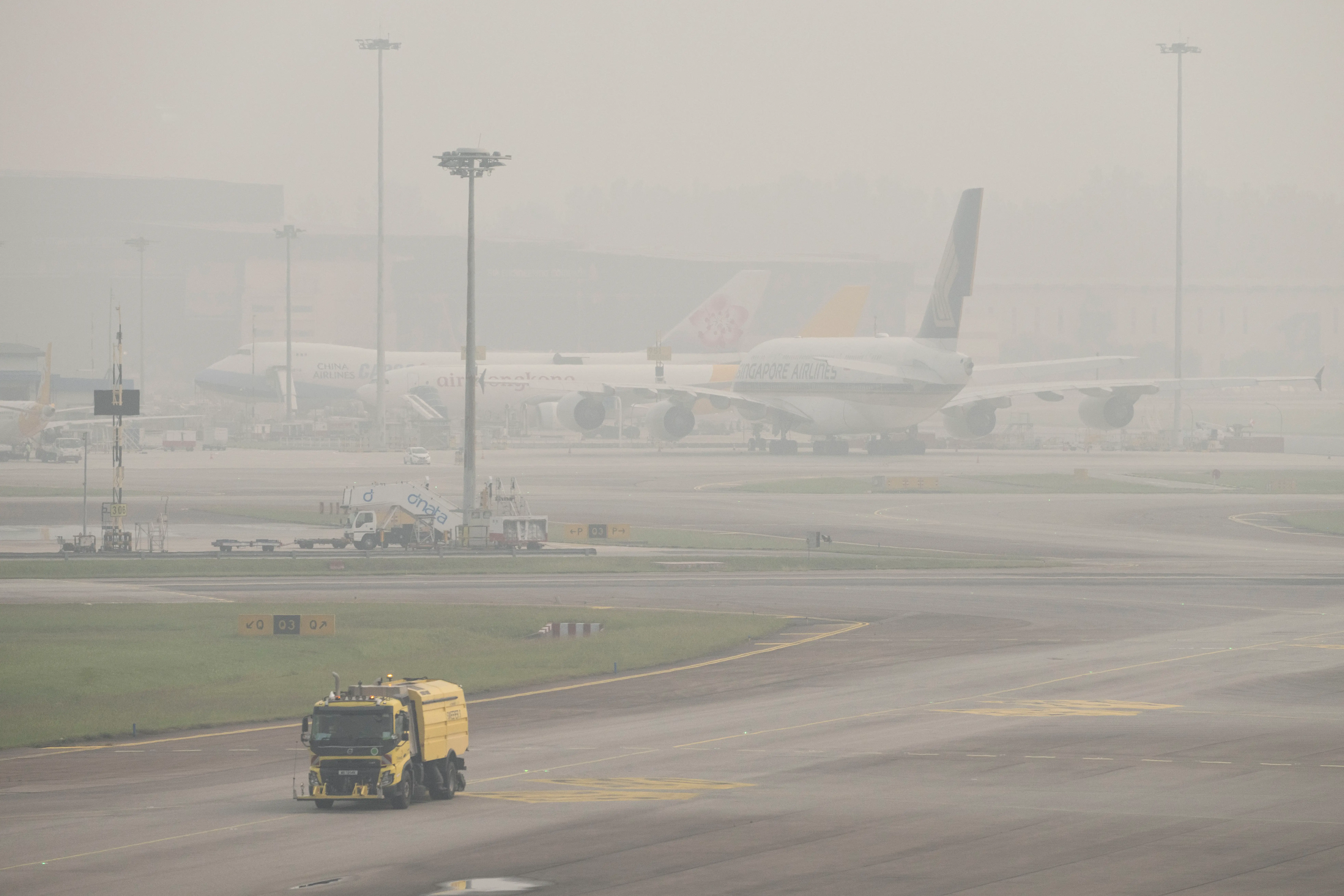 A cleaning truck drives past airplanes parked on the tarmac at Changi Airport in Singapore on October 16, 2026, as the country continues to be shrouded in haze caused by fires in Indonesia. .
