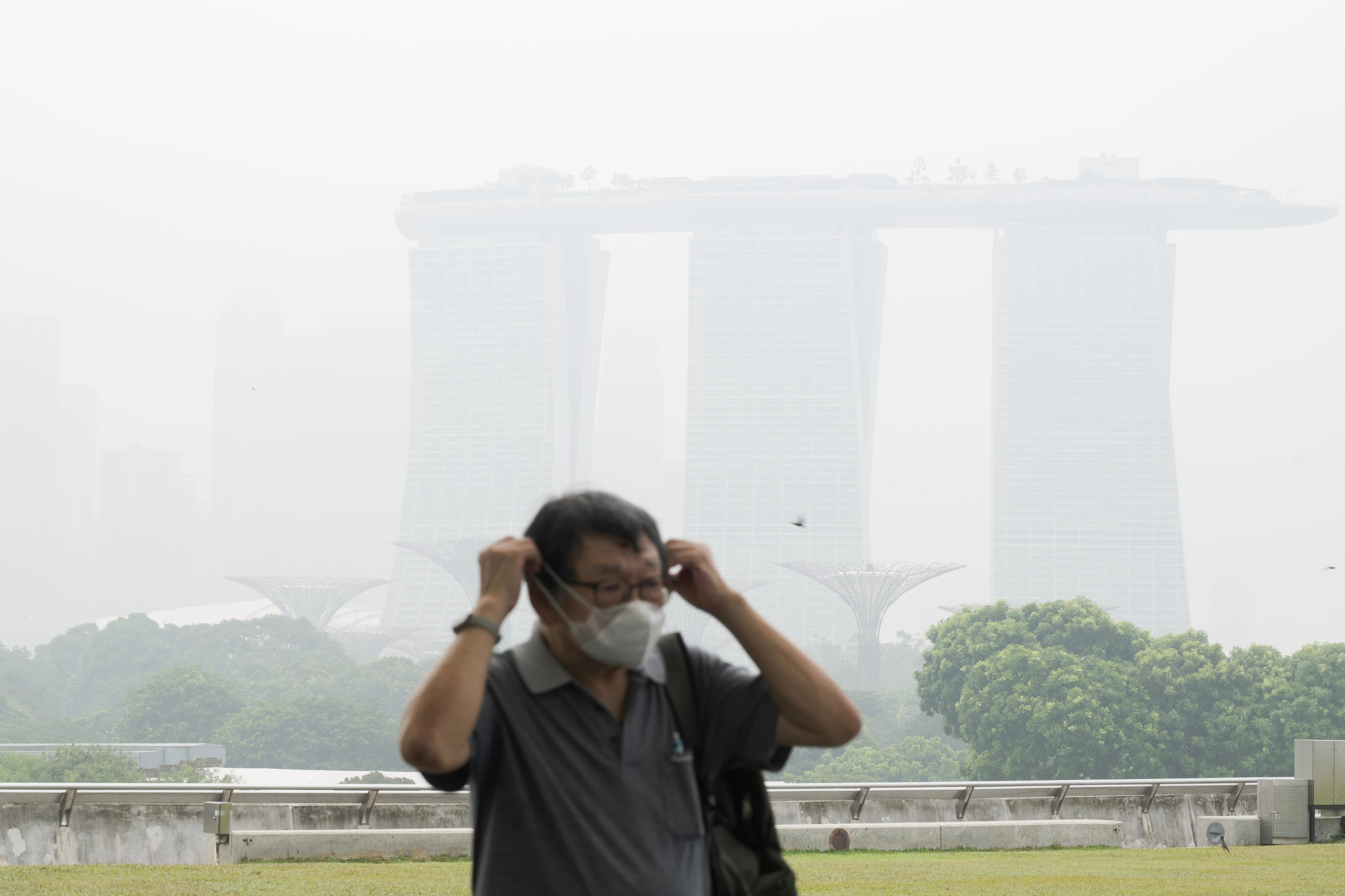 A man wears a mask as the Singapore skyline is shrouded in haze on October 15, 2026.