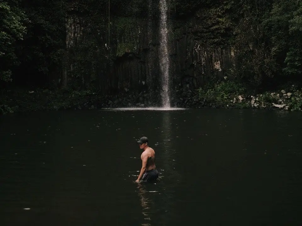 A man standing in the waterfall in Australia.