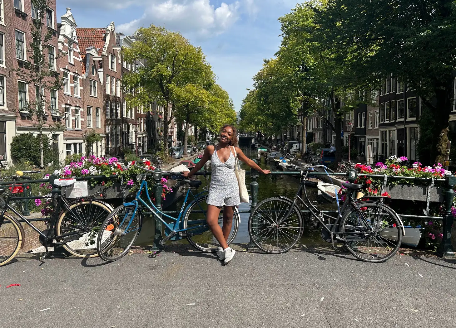 The writer posing with bicycles in front of canals, trees, and houses.