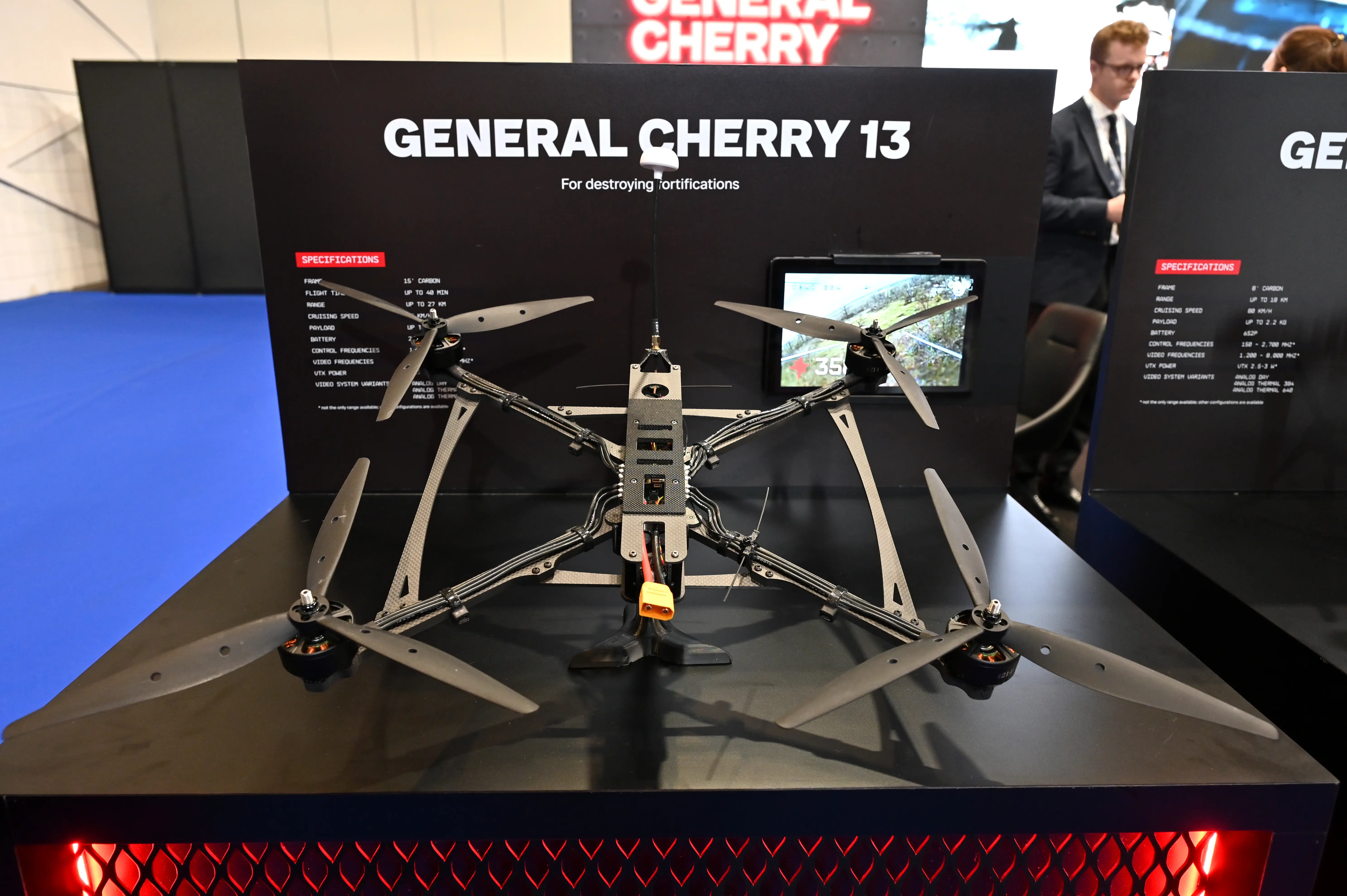 Large multi-rotor drone displayed on a trade-show stand beneath a “GENERAL CHERRY 13” sign.