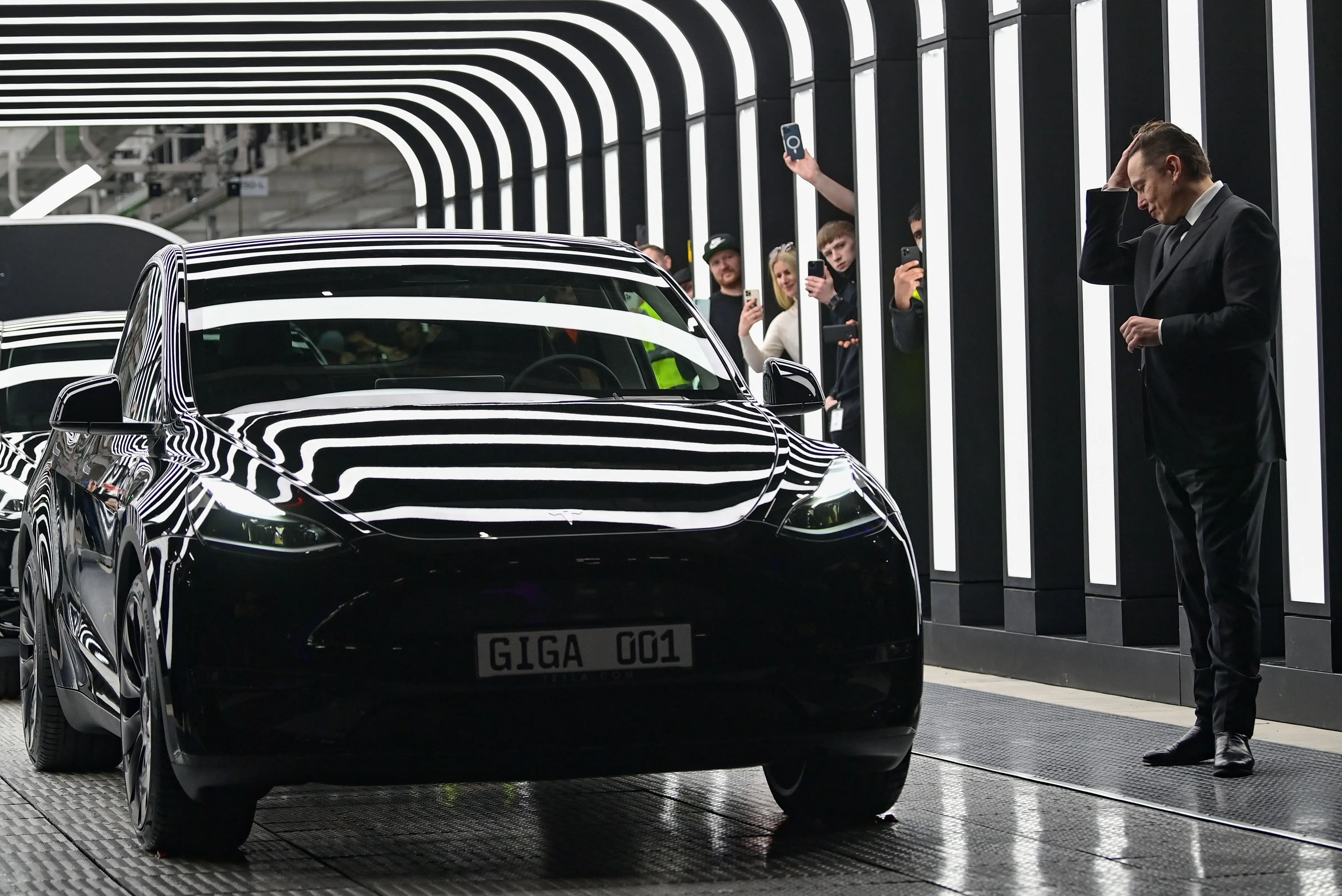 Elon Musk looking at a Tesla car