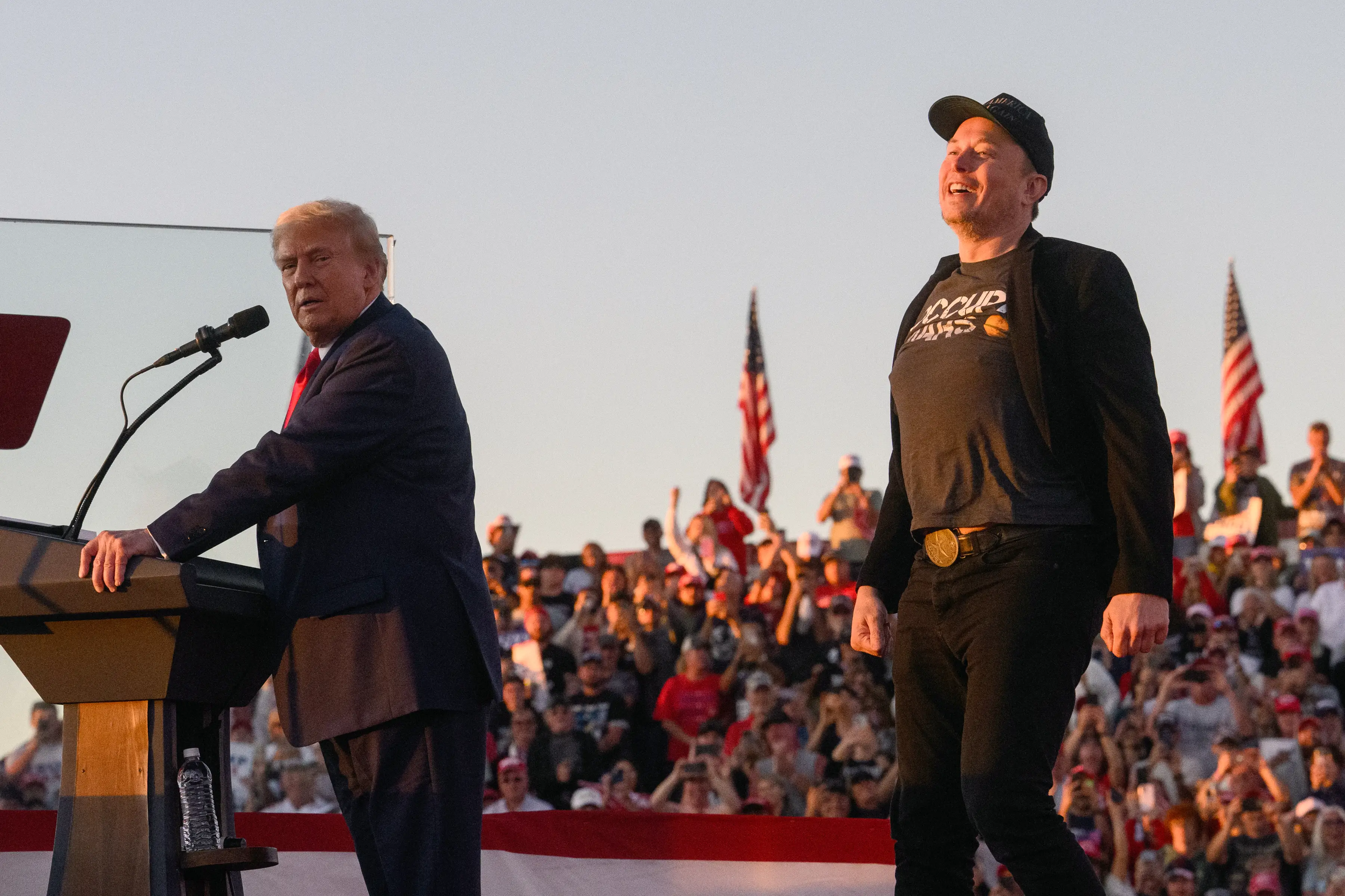 Elon Musk, chief executive officer of Tesla Inc., right, joins former US President Donald Trump on stage during a campaign event at the Butler Farm Show in Butler, Pennsylvania, US, on Saturday, Oct. 5, 2024. Republican nominee Donald Trump rallied supporters at the site of a July assassination attempt, returning to the Pennsylvania venue where a gunman's bullet bloodied his ear and upended the presidential campaign. Photographer: Justin Merriman/Bloomberg via Getty Images