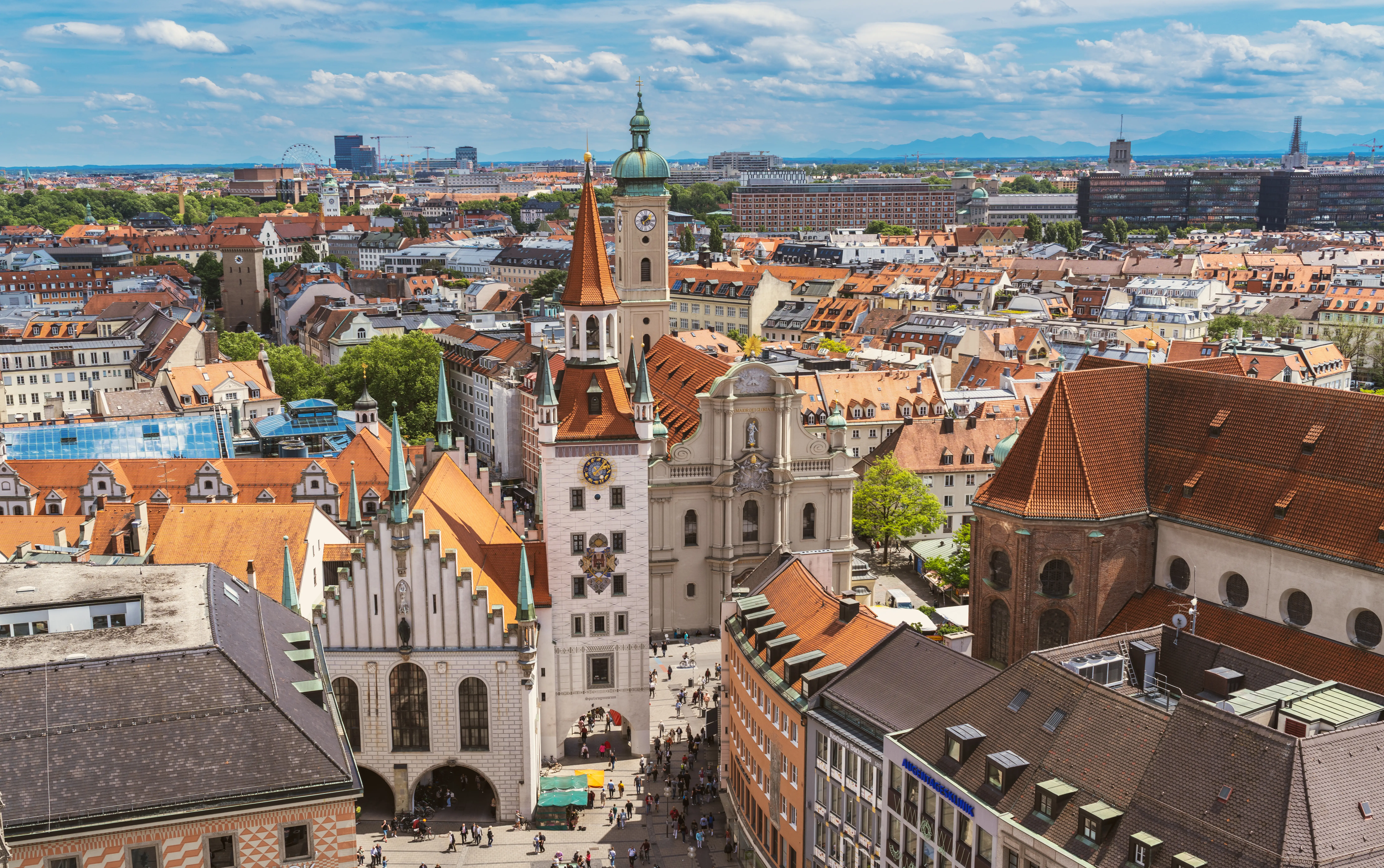 Aerial view of Munich’s old town with the Altes Rathaus tower and red-tiled rooftops under a cloudy sky.