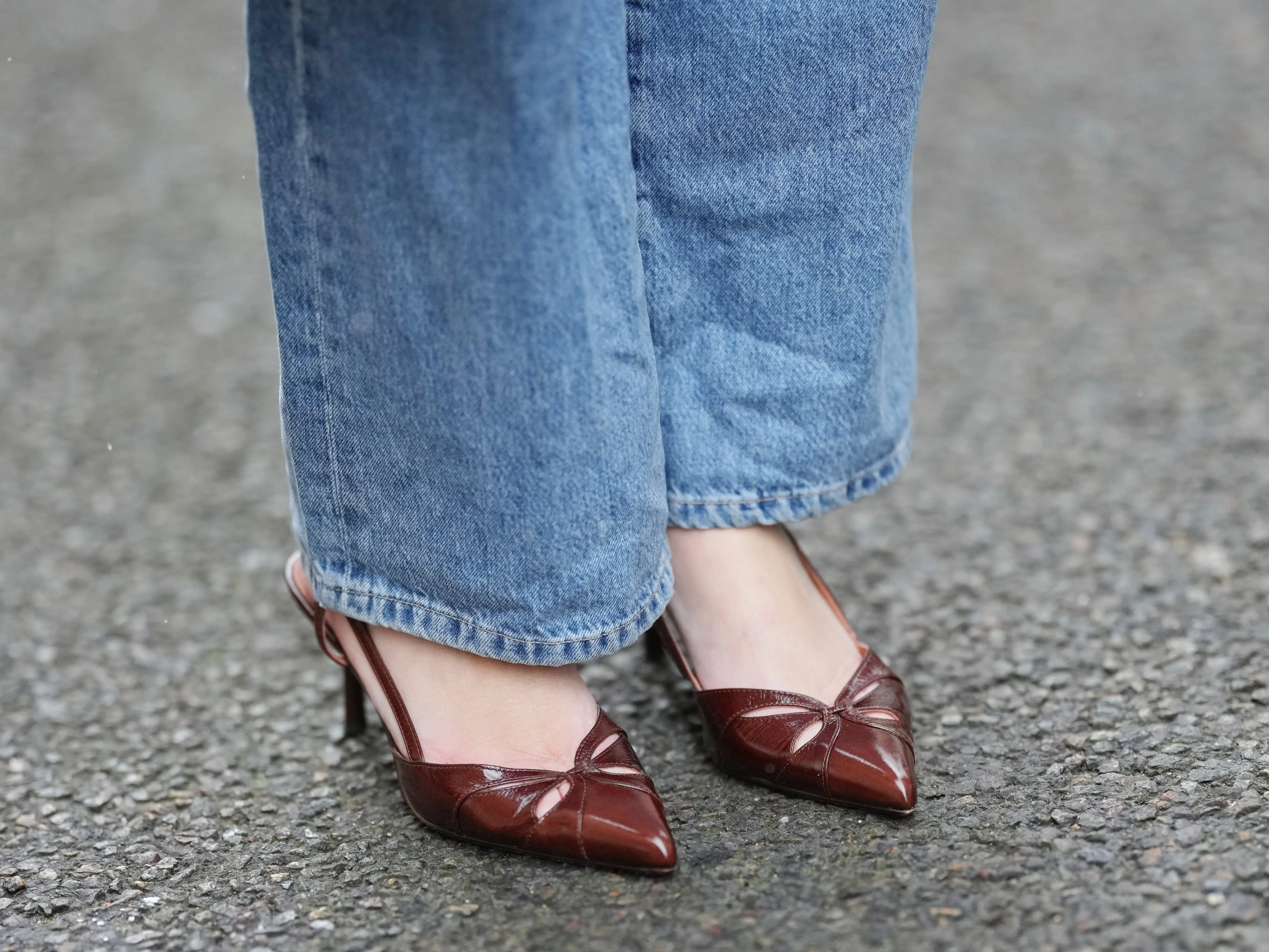 A close-up of a person wearing pointed-toe heels with medium-wash jeans.